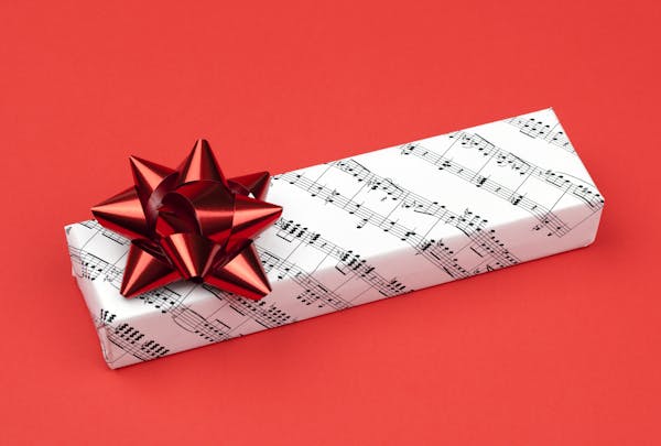 "Gift box with sheet music wrapping paper, on a red background with plenty of copy space.The wrapping paper is a section of Beethoven's Symphony Numbe