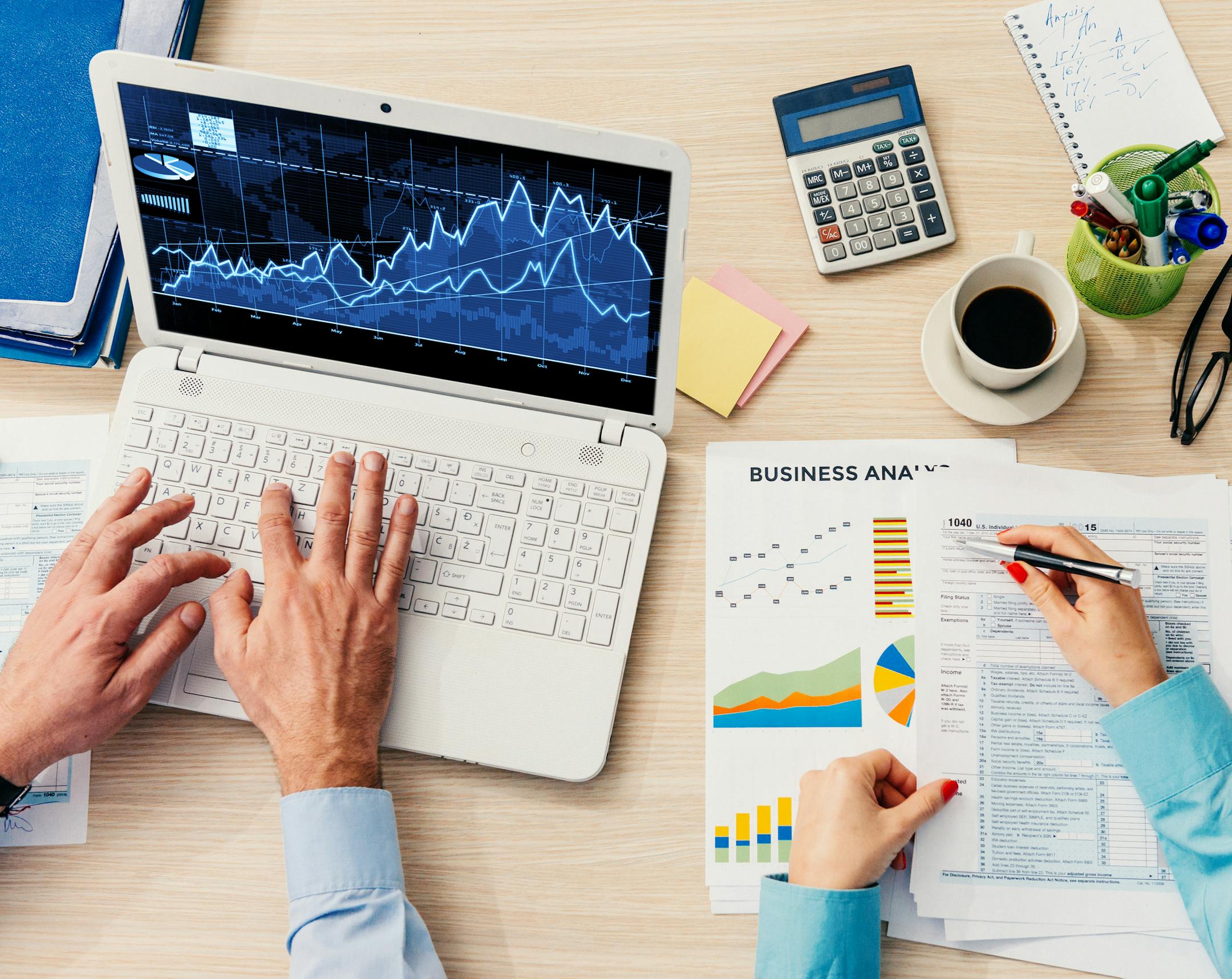 Two business people in office working on business reports, financial statements and tax form 1040 filling out. Teamwork in office with two unrecognizable business persons. Image taken with Nikon D800, developed from RAW in XXXL size. Location: Novi Sad, Serbia, Central Europe, Europe