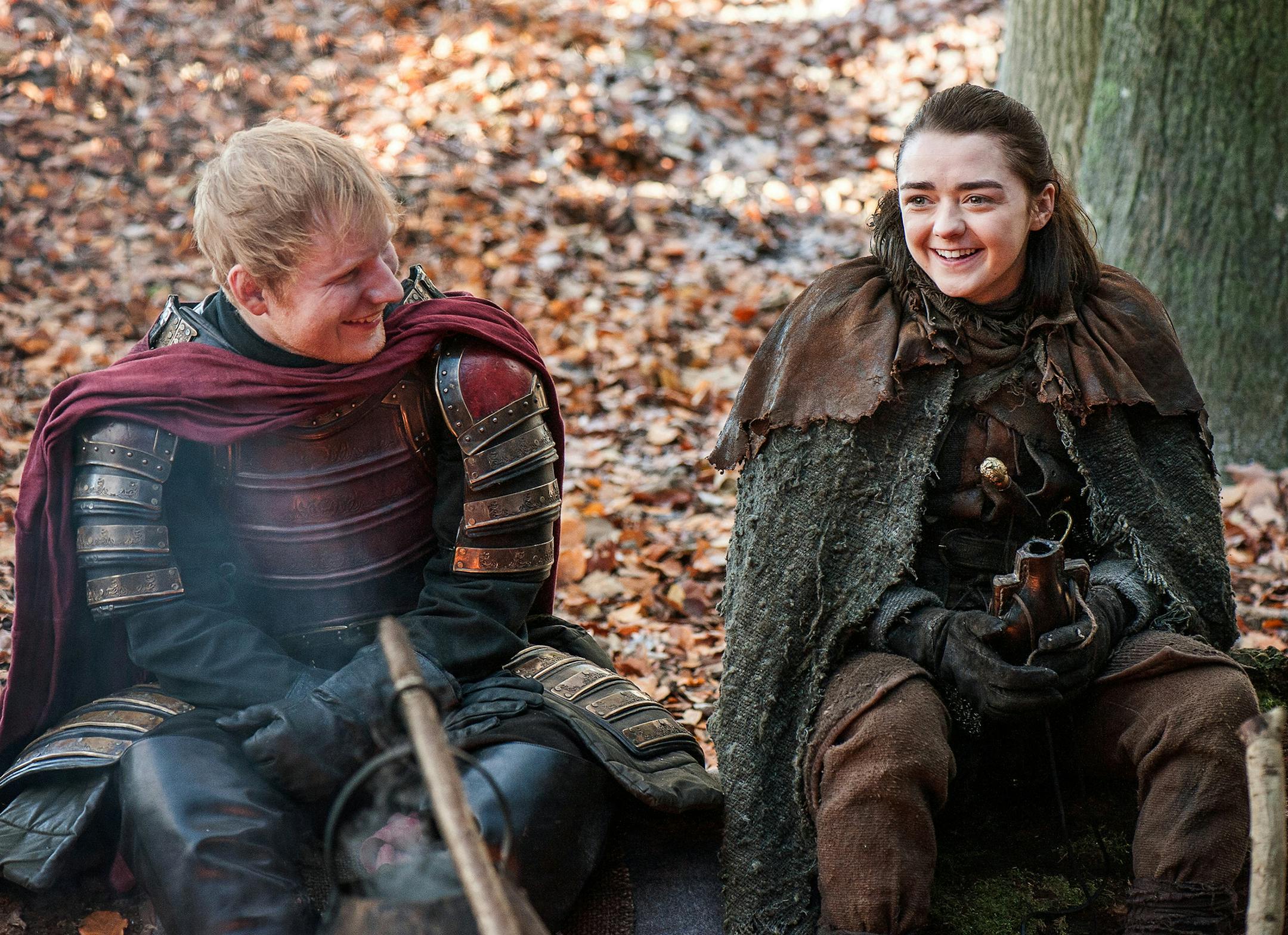 This image released by HBO shows Ed Sheeran, left, and Maisie Williams in a scene from "Game of Thrones." Sheeran appeared as a Lannister soldier leading a group in song in the season premiere of the hit HBO fantasy drama, which debuted on the premium cable channel Sunday night. (Helen Sloan/HBO via AP)