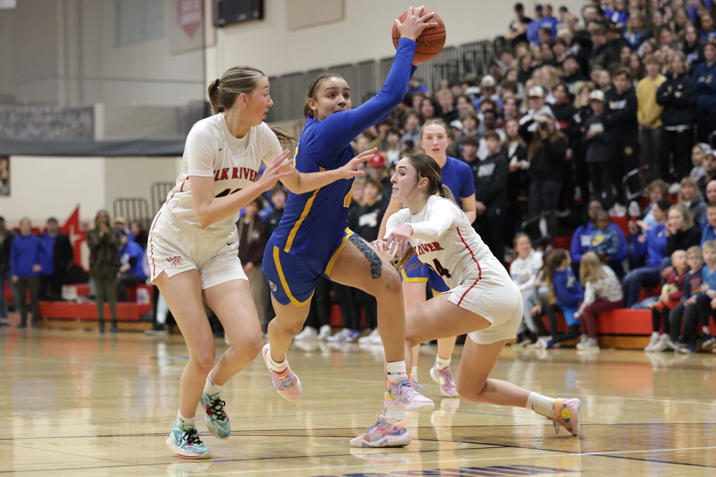 St. Michael-Albertville's Tessa Johnson (4) drives the lane between a pair of Elk River defenders. Johnson led the field with 23 pints in the first half. Photo by Cheryl A. Myers, SportsEngine