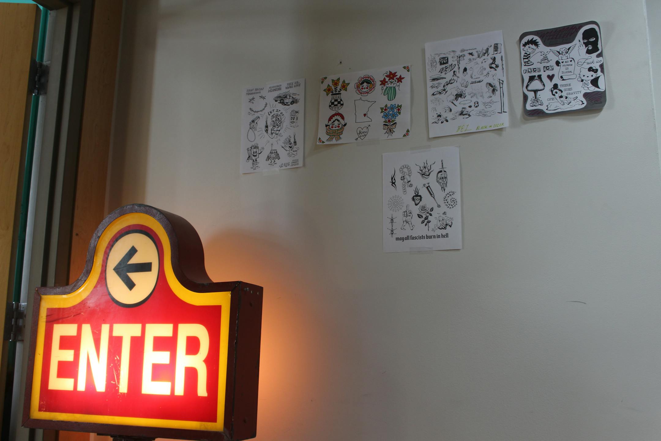 Tattoo designs taped to the entrance of Kaleidoscope Tattoo Collective show new designs decrying Immigration and Customs Enforcement in Minnesota.