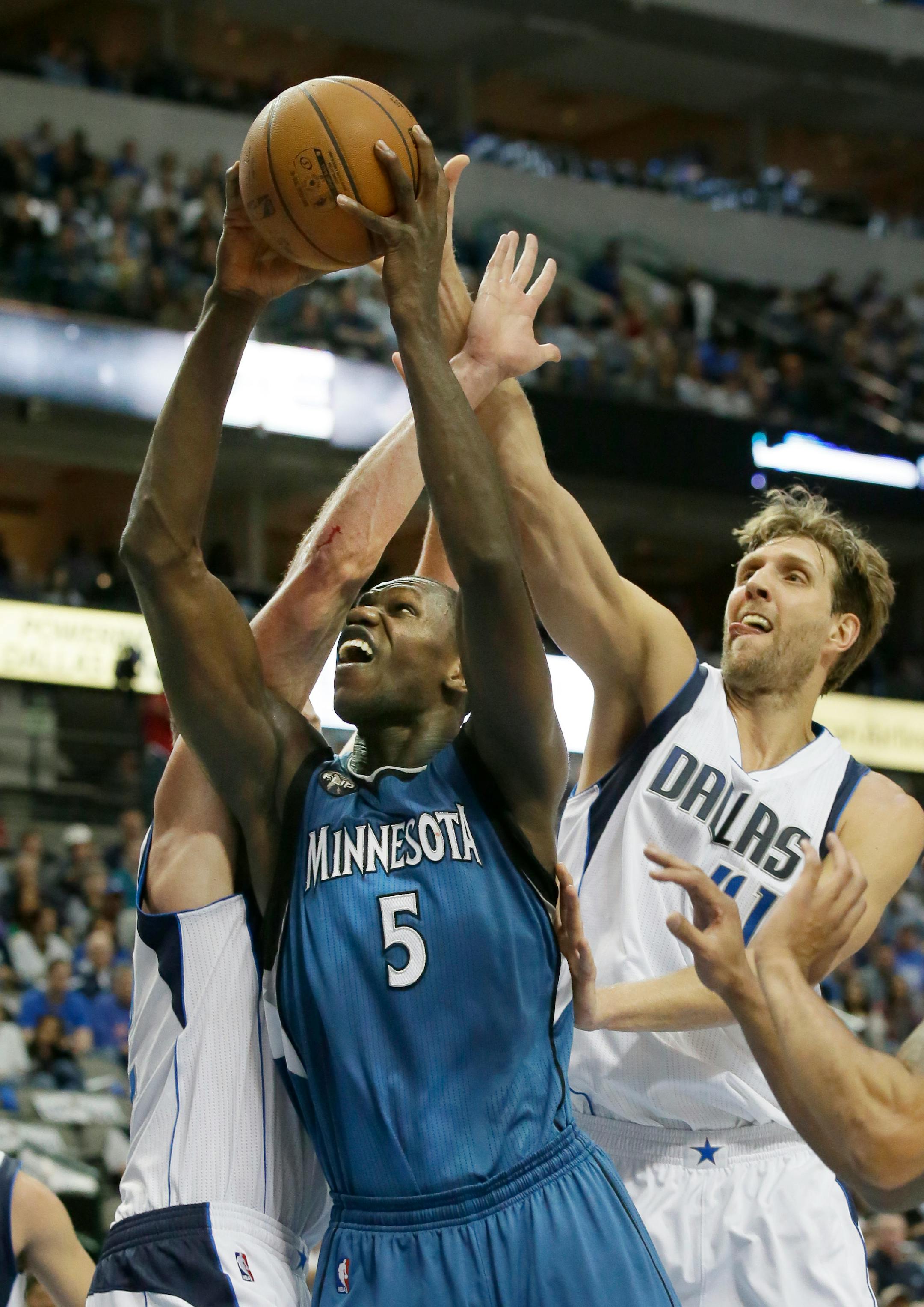 Minnesota Timberwolves center Gorgui Dieng (5) drives between Dallas Mavericks defenders Dirk Nowitzki (41) and David Lee during the first half of an NBA basketball game Sunday, Feb. 28, 2016, in Dallas. (AP Photo/LM Otero)