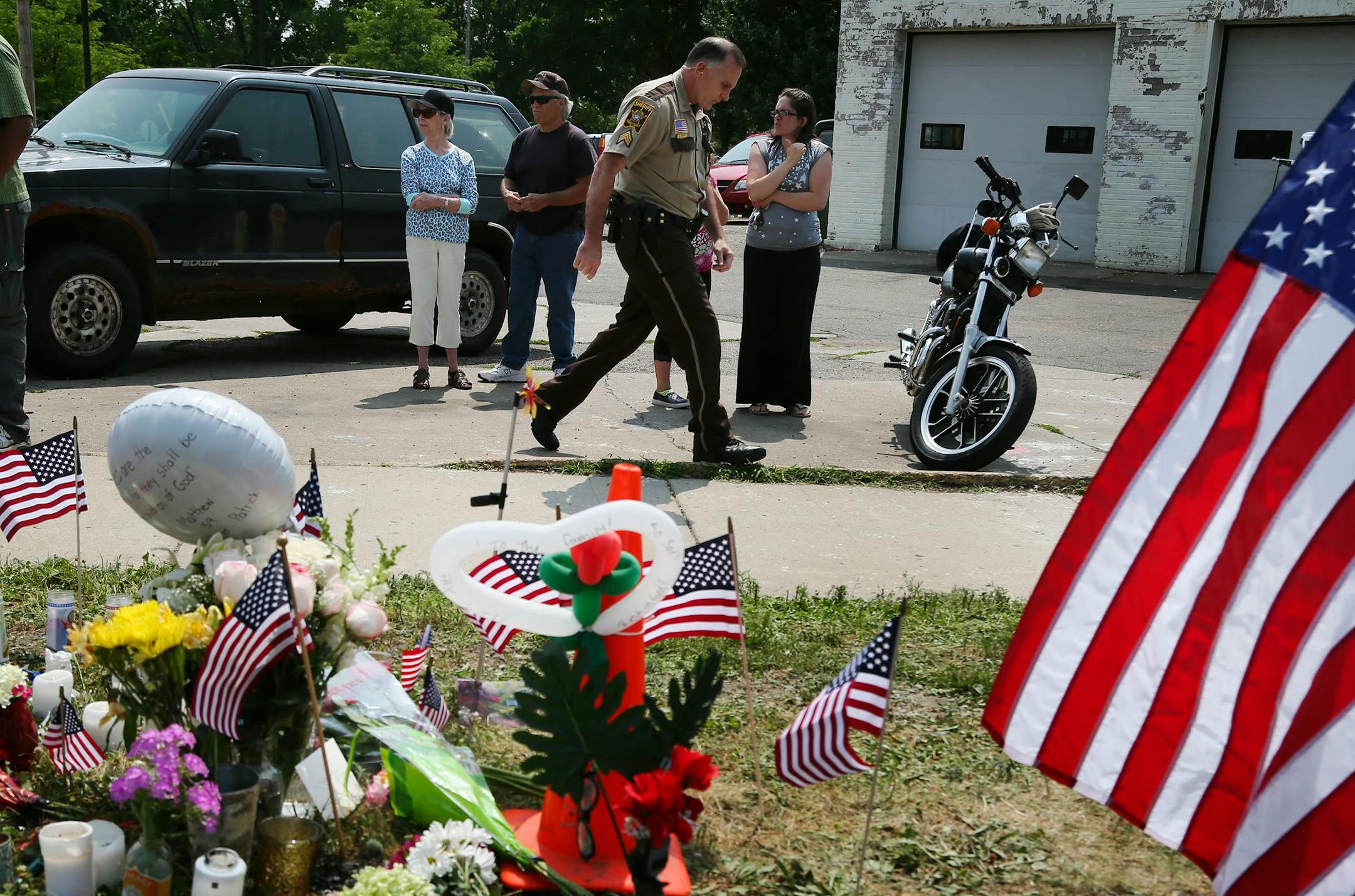 In this July 31, 2014, file photo, a police officer and mourners gather in West St. Paul at the scene of a fatal shooting of Mendota Heights police officer Scott Patrick.