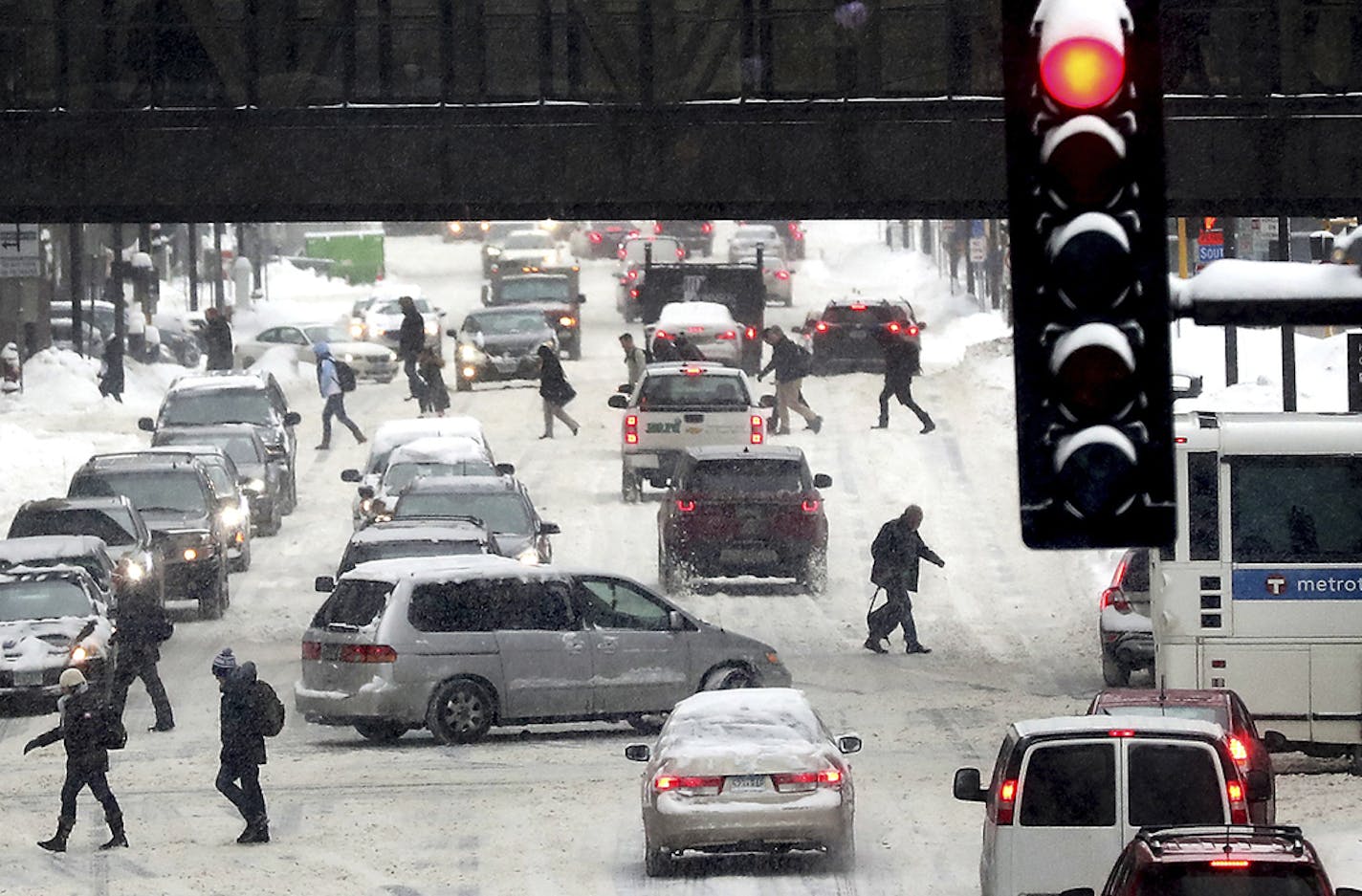 Pedestrians and motorist navigate snowy streets along Third Ave. S., Tuesday, Feb. 12, 2019, in Minneapolis. (David Joles/Star Tribune via AP)