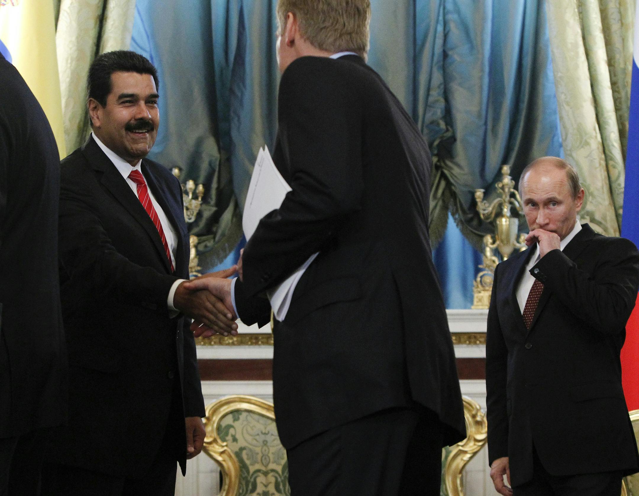Russia's President Vladimir Putin, right, looks on as his Venezuelan counterpart Nicolas Maduro, left, shakes hands with presidential spokesman Dmitry Peskov during a meeting at the Kremlin in Moscow, Tuesday, July 2, 2013. Russian news agencies Tuesday quoted President Vladimir Putin's spokesman Dmitry Peskov as saying that Snowden withdrew his request when he learnt about the terms Moscow has set out. (AP Photo/Maxim Shemetov, pool)