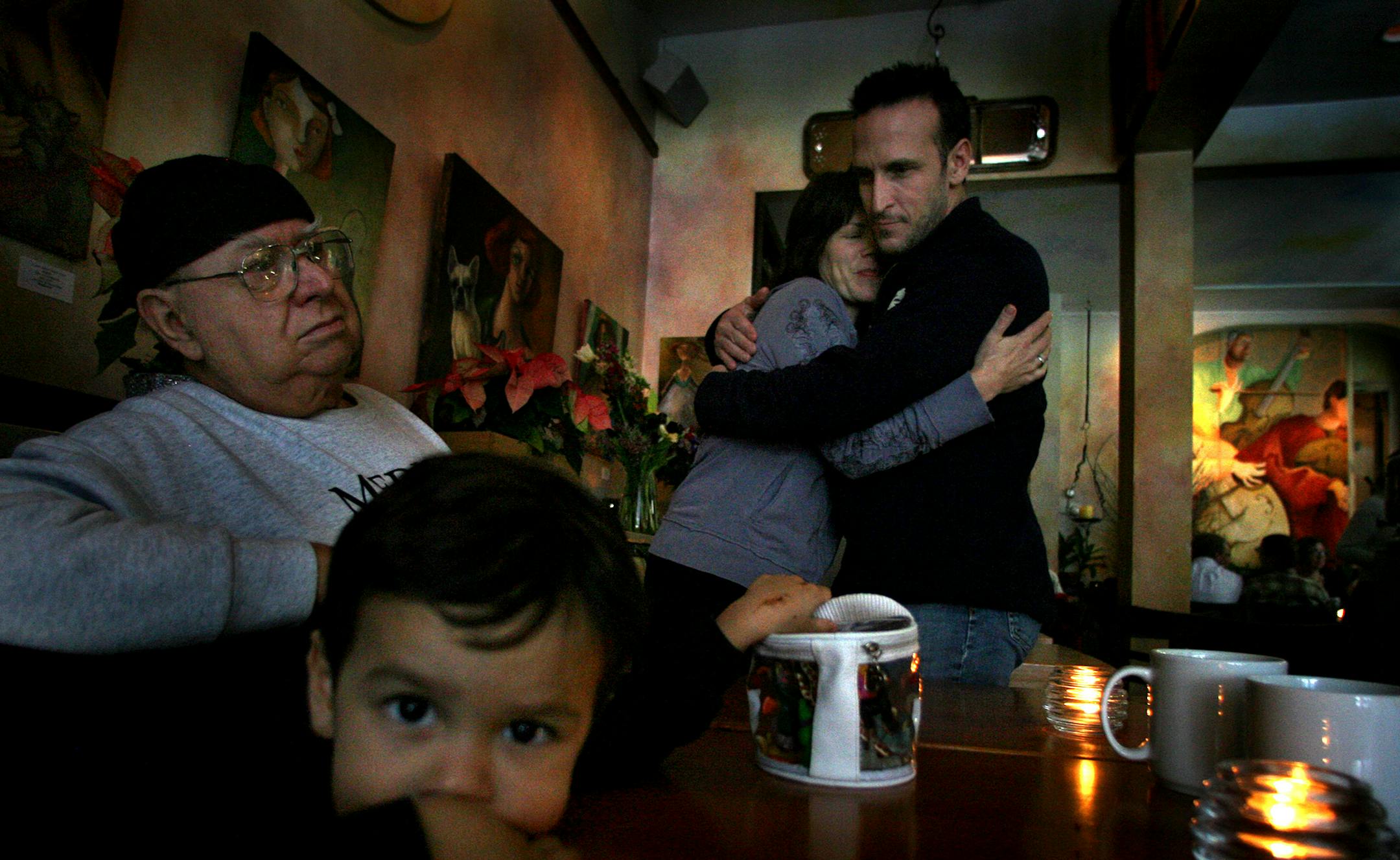 Carrie Gustafson, co-owner of Sonny�s Creama Caf� in Minneapolis was embraced by family friend, John Liljequist (cq). Liljequist�s son, Kai, 2, and father, Henry (Hank) joined him at the caf� Saturday morning. Gustafson is the longtime partner of Ron Siron, son of the Caf�s namesake who recently passed away. Minneapolis, MN., Friday, 10/5/2001. This is a story of how one simple economic outcome of the WTC attack can affect many people economically. The focus is the in-flight meal: a slice of piz