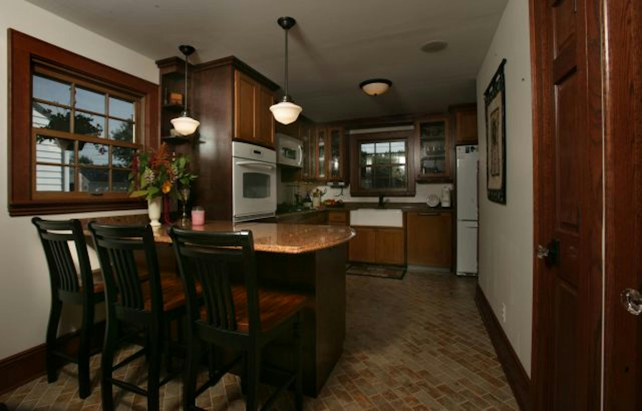 Adding on to the back of the house allowed Janet Graves to expand and update her tiny kitchen with quartz countertops, a farmhouse sink, Arts and Crafts-style oak and maple cabinets and a dining peninsula. The former hall closet, right, was converted into a kitchen pantry.