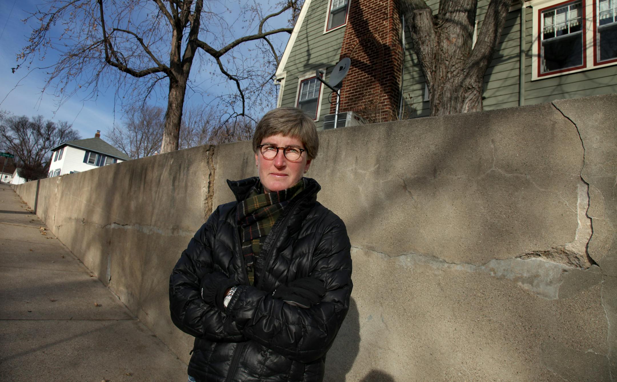 Elizabeth Howell stood near a cracked retaining wall near her home, Wednesday, November 30, 2011. For three years the city of Minneapolis has been demanding that Elizabeth Howell repair her retaining wall. But Howell says the wall is on city property and she has plat documents to prove it. The city has threatened to do it themselves and assess her, but when Howell and her attorney show the city that it is the city's land, they seem to back down. Now, Elizabeth Howell has sued the city to tell th