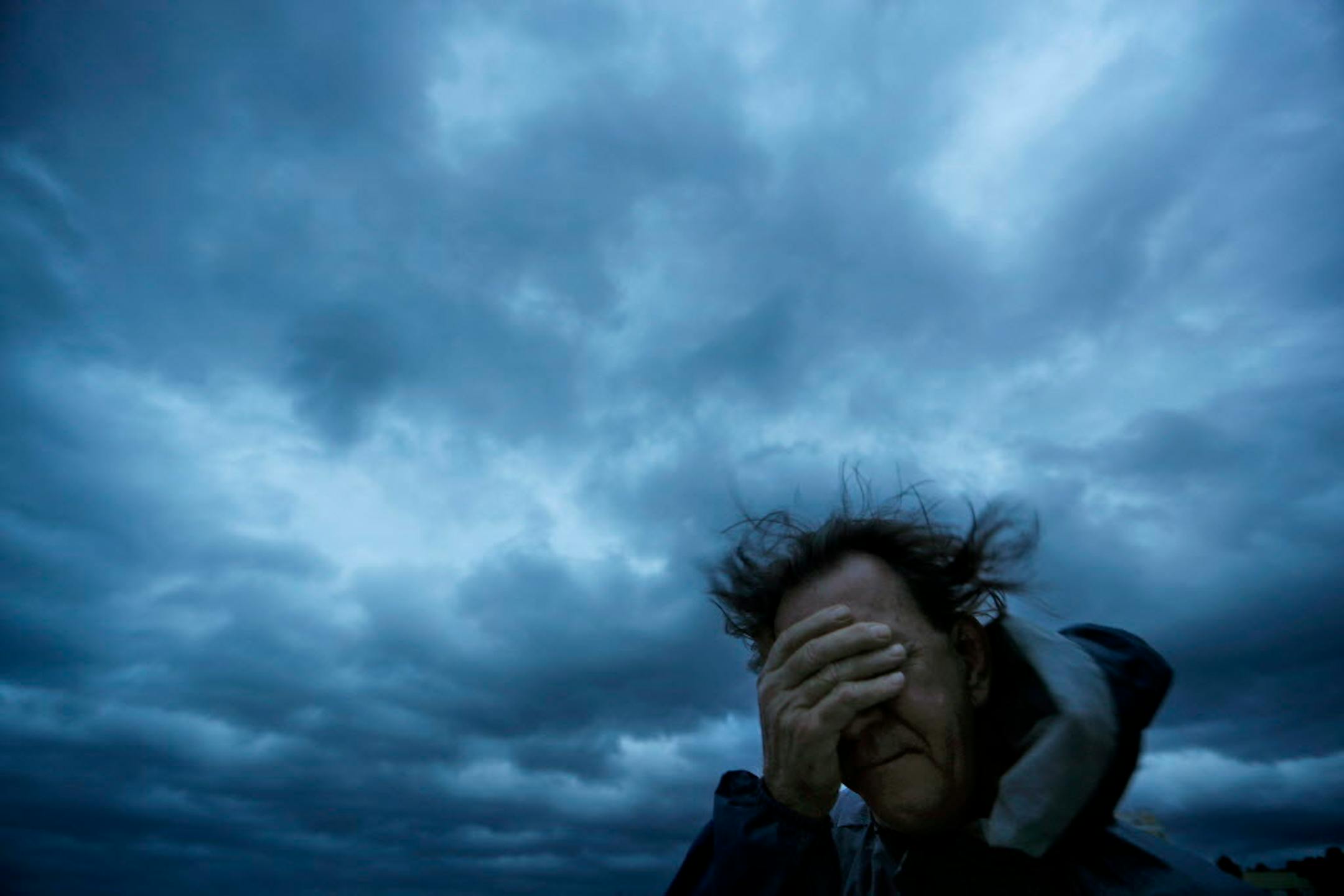 Russ Lewis covers his eyes from a gust of wind and a blast of sand as Hurricane Florence approaches Myrtle Beach, S.C., on Friday, Sept. 14, 2018.