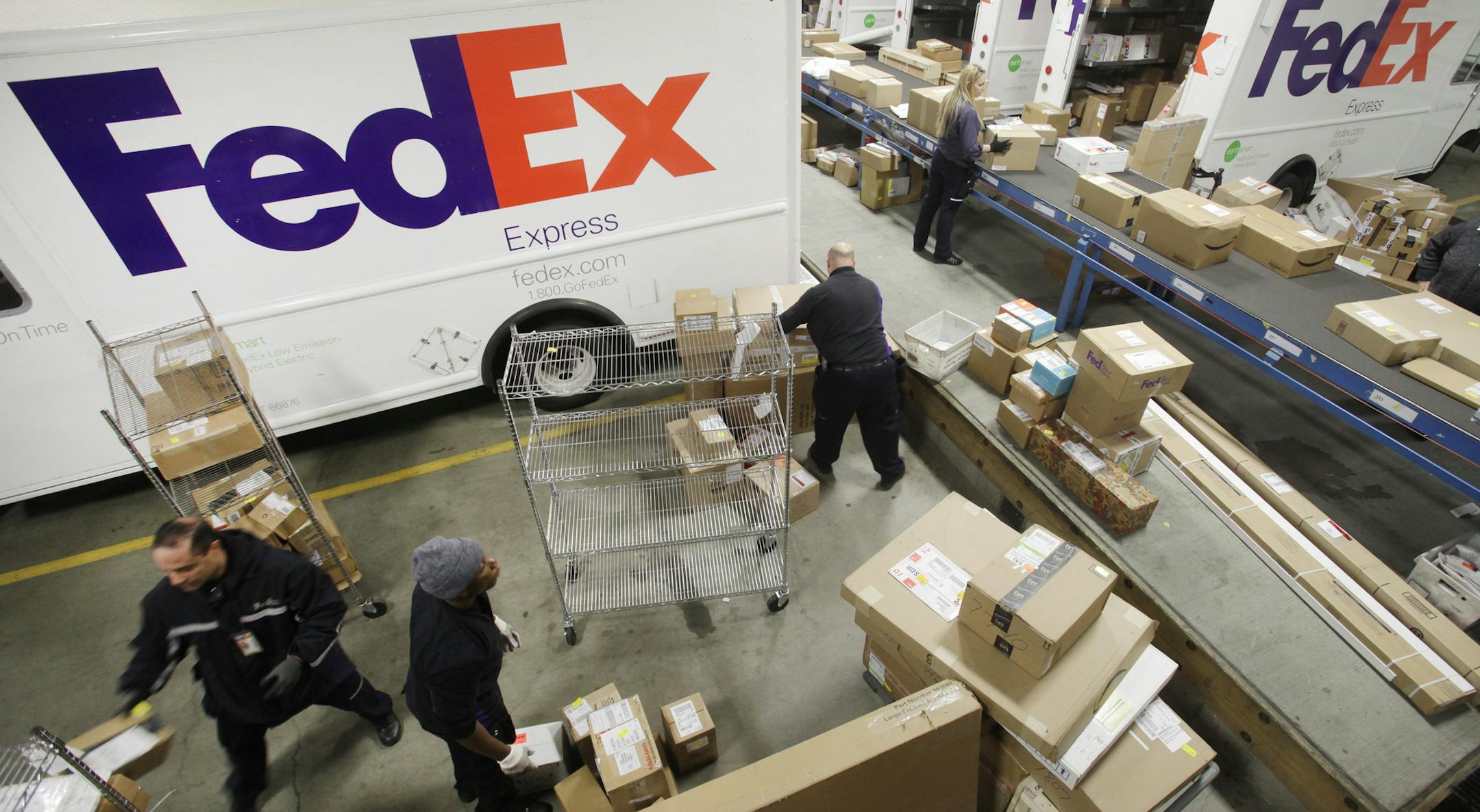 FILE - In this Dec. 15, 2014, file photo, employees pull boxes from a conveyor belt and fill their trucks for deliveries at a FedEx sorting facility in the Bronx borough of New York. FedEx reports financial results Tuesday, Sept. 20, 2016. (AP Photo/Mark Lennihan, File)