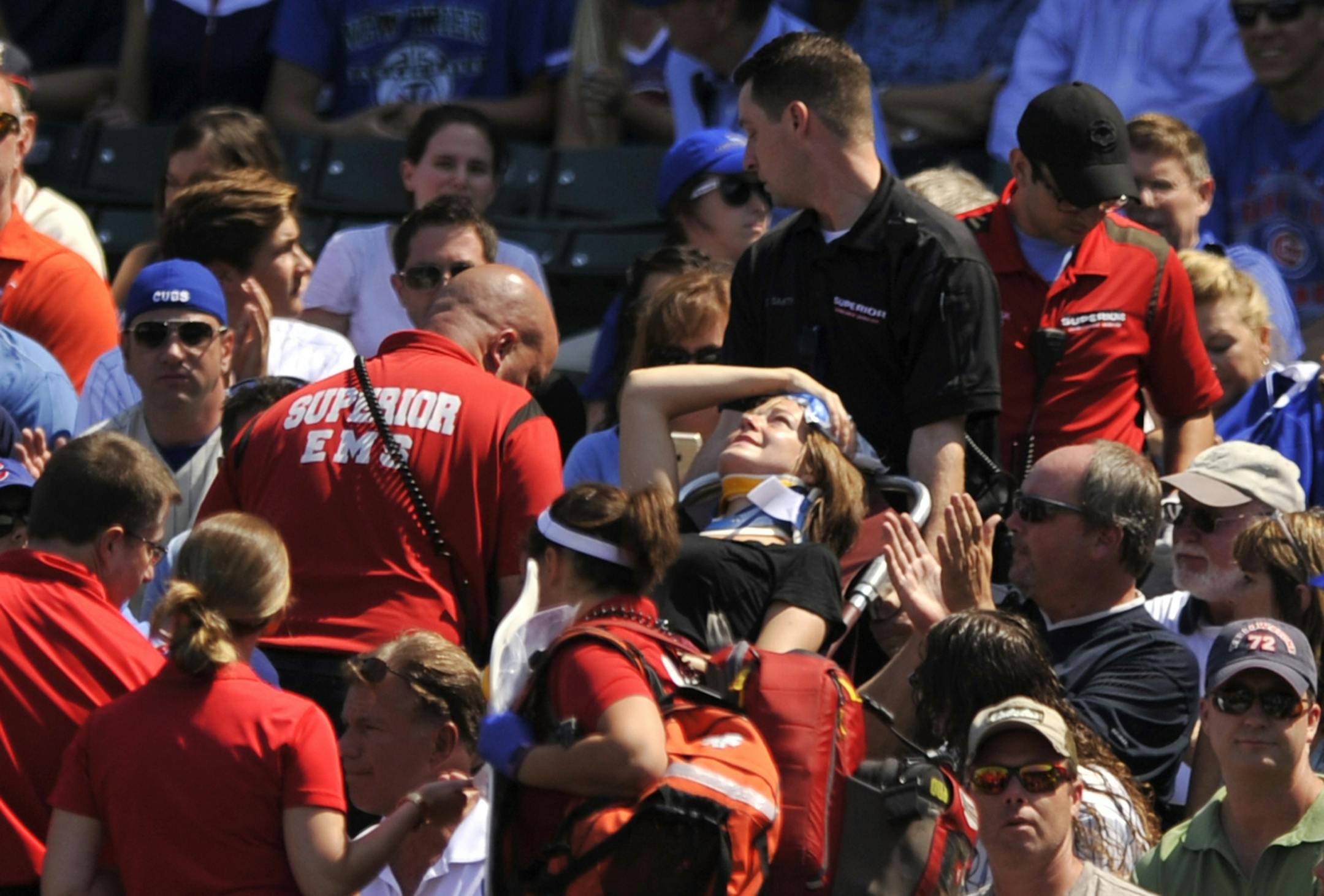 A fan is carried away after being hit a by a line-drive foul ball during the first inning of a baseball game between the Chicago Cubs and the Atlanta Braves at Wrigley Field, Sunday, Aug. 23, 2015, in Chicago. (AP Photo/Paul Beaty)