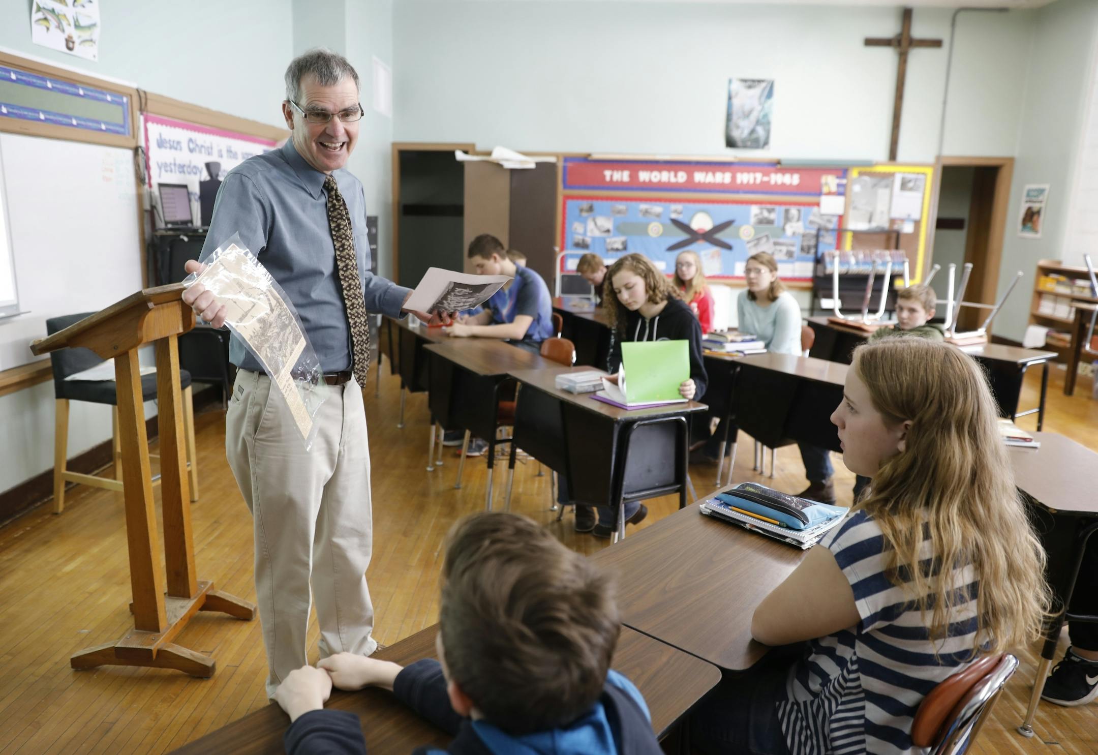 History teacher Dean Scheele holds up some photos and newspaper articles as the class discusses what to bring with them to meet Don Givens' nephew in Chicago.