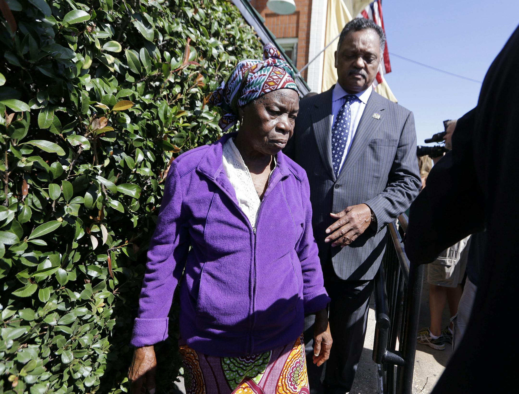 Nowai Korkoya, mother of Ebola patient Thomas Eric Duncan, walks with the Rev. Jesse Jackson after they spoke to reporters, Tuesday, Oct. 7, 2014, in Dallas. Duncan's family has gathered in Dallas to check on his condition. (AP Photo/LM Otero)