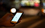 An Uber customer checked the status of his ride on his phone while waiting at the intersection of Lagoon Avenue and Hennepin Avenue late Saturday nigh