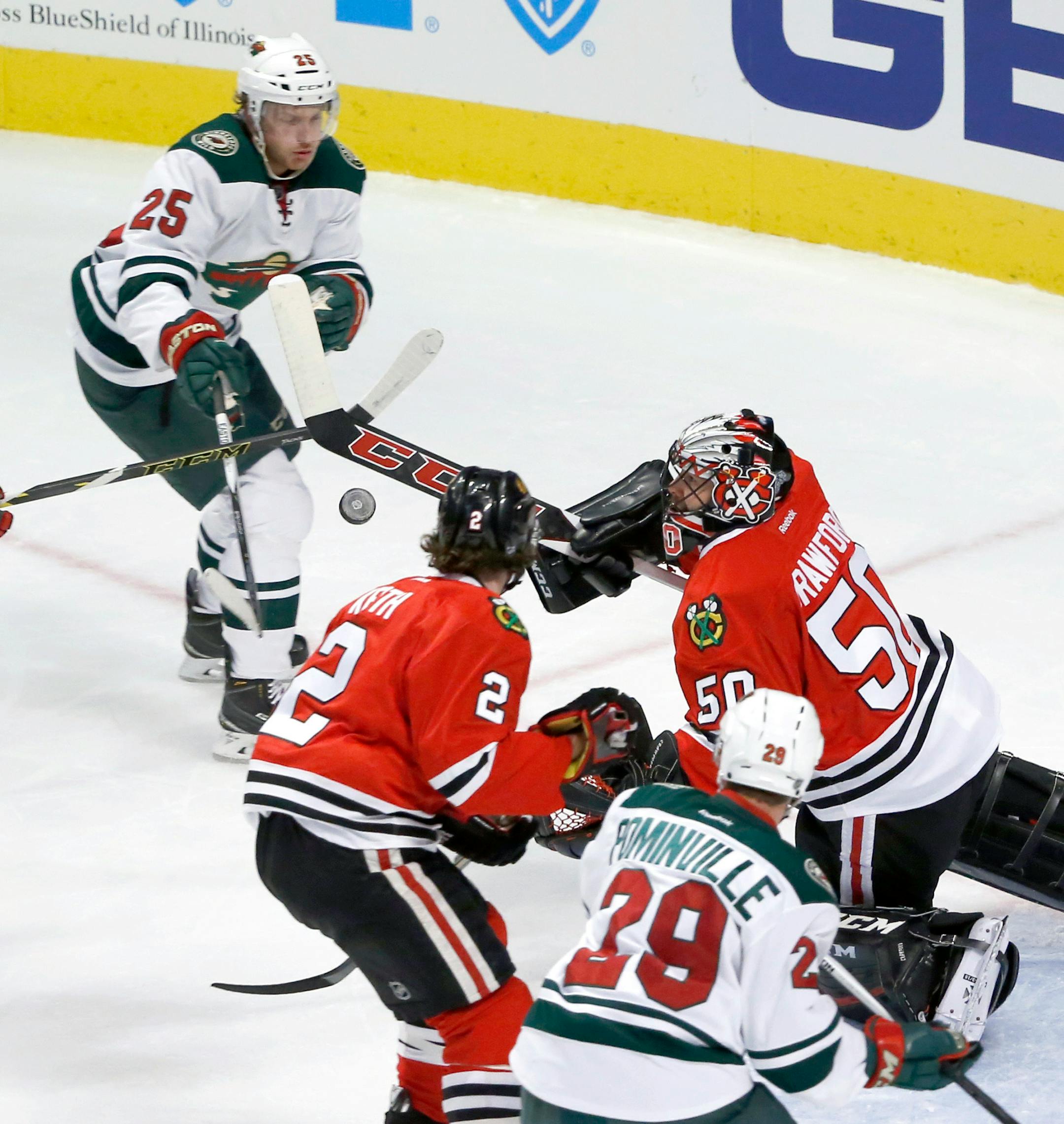 Chicago Blackhawks goalie Corey Crawford (50) knocks the puck down with his stick as Minnesota Wild defenseman Jonas Brodin (25) Duncan Keith (2) and Jason Pominville watch, during the first period of an NHL hockey game Tuesday, Dec. 1, 2015, in Chicago. (AP Photo/Charles Rex Arbogast)