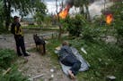 A man lies on the ground as he watches his burning house destroyed by a Russian airstrike in Vovchansk, Ukraine, on Saturday, May 11, 2024.