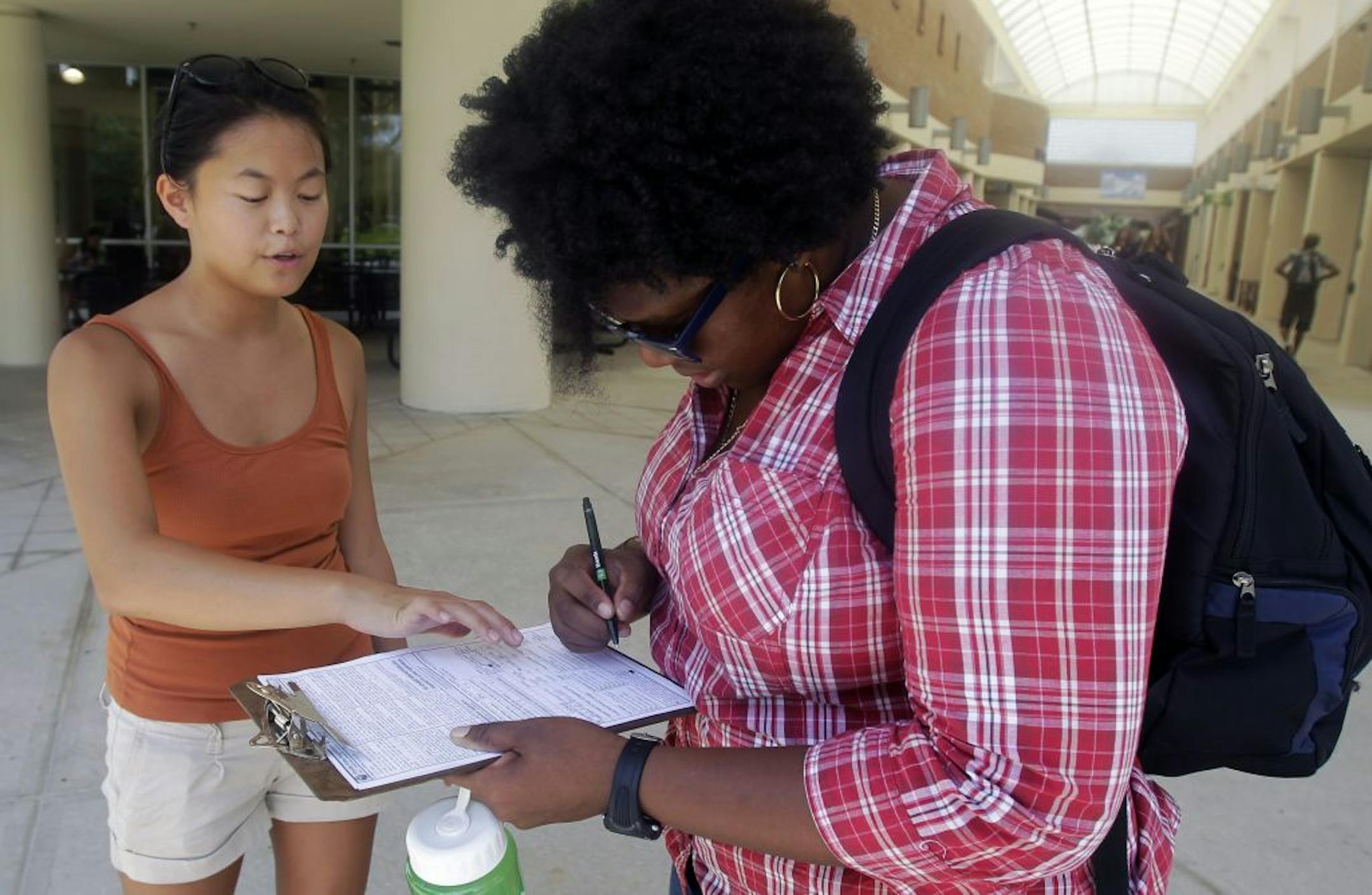 In this Tuesday, July 31, 2012, photo, Aubrey Marks, left, helps a University of Central Florida student to register to vote in Orlando, Fla.