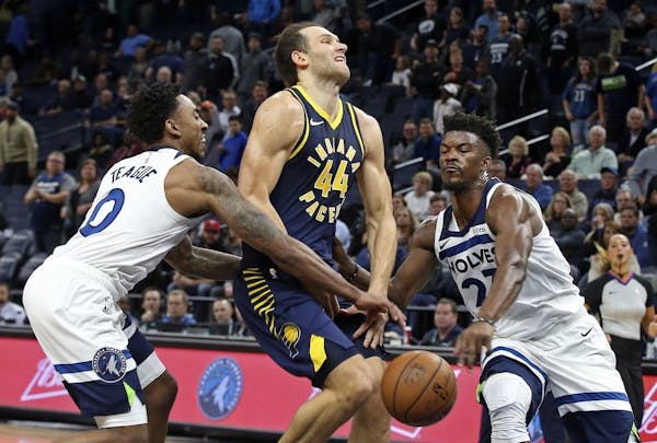 Minnesota Timberwolves' Jeff Teague, left, and Jimmy Butler, right, break up a drive by Indiana Pacers' Bojan Bogdanovic, of Croatia, in the second ha