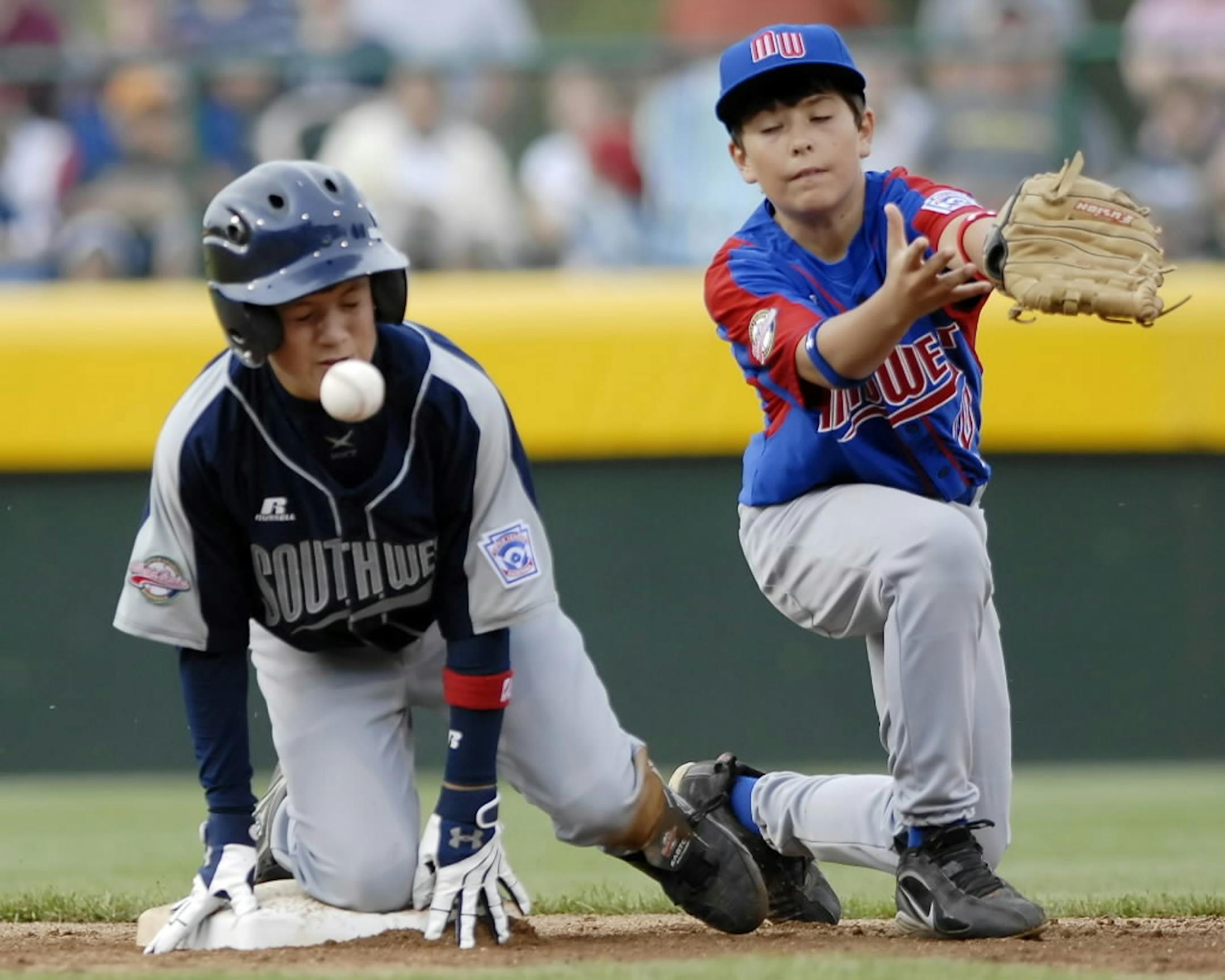 Lubbock, Texas, baserunner Stephen Smith, left, slides into second with a third-inning double and is hit in the face as the throw from right field gets by Coon Rapids, Minn., shortstop Jacob Bruner during Little League World Series baseball action in South Williamsport, Pa., Saturday, Aug. 18, 2007. Smith left the game with the injury.