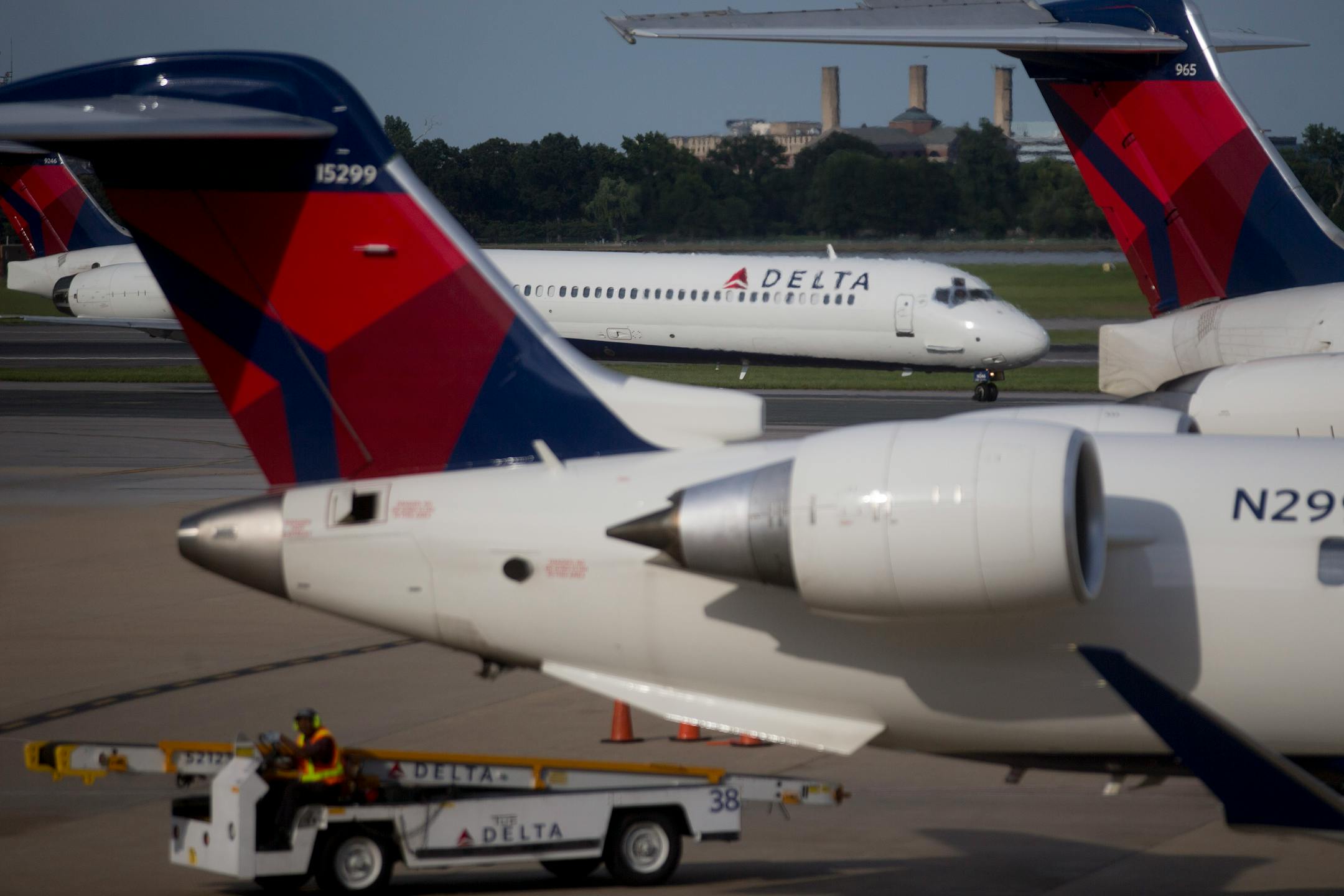 A Delta Air Lines Inc. airplane moves past Delta airplanes parked at gates of Ronald Reagan National Airport in Washington, D.C., U.S., on Wednesday July 16, 2014. Delta Air Lines Inc., the third-largest U.S. airline, is expected to report second quarter earnings figures on July 23. Photographer: Andrew Harrer/Bloomberg