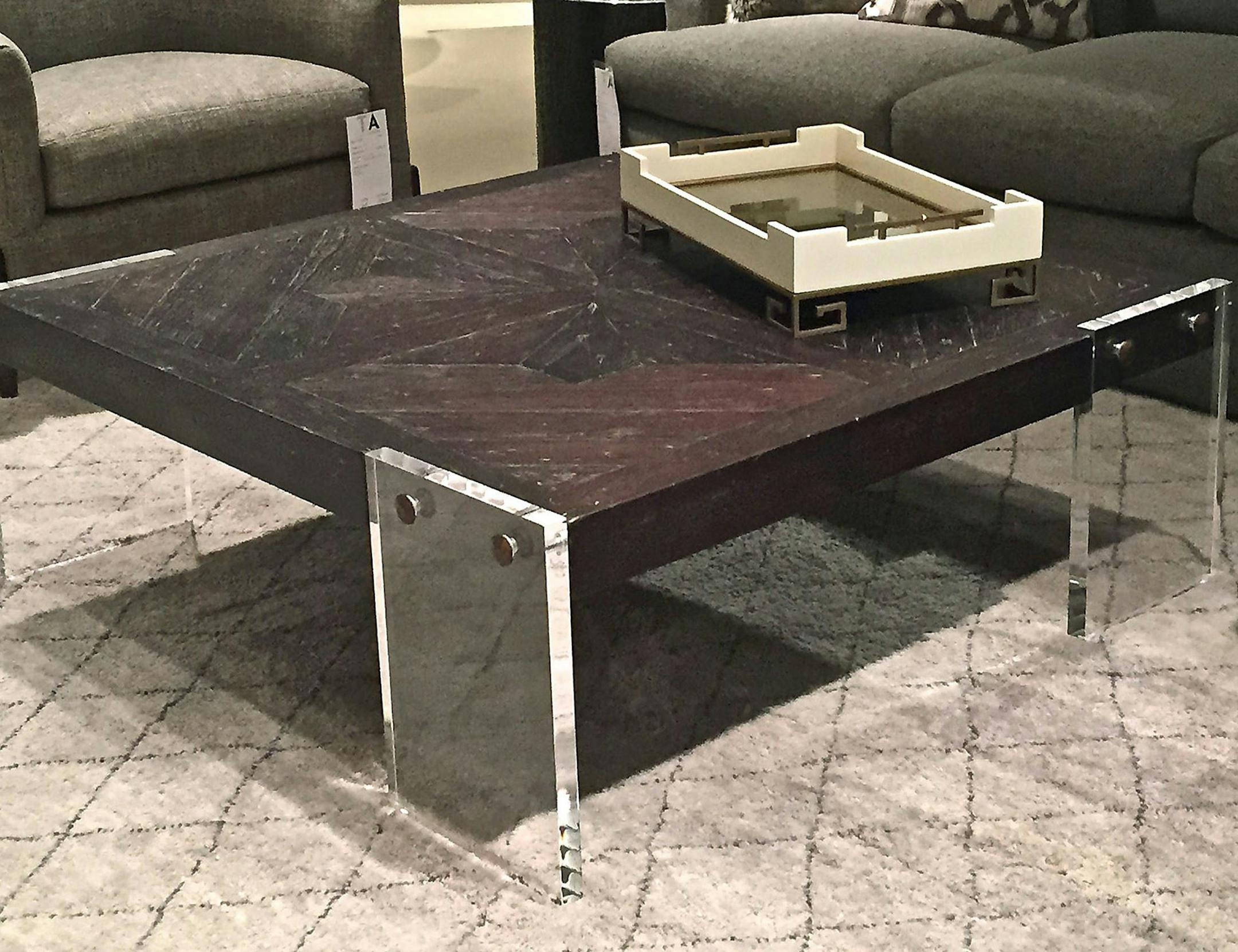 The Levitate cocktail table by Theodore Alexander seems to be doing just that with a mahogany and acacia top floating on acrylic legs. (Patricia Sheridan/Pittsburgh Post-Gazette/TNS) ORG XMIT: 1187682