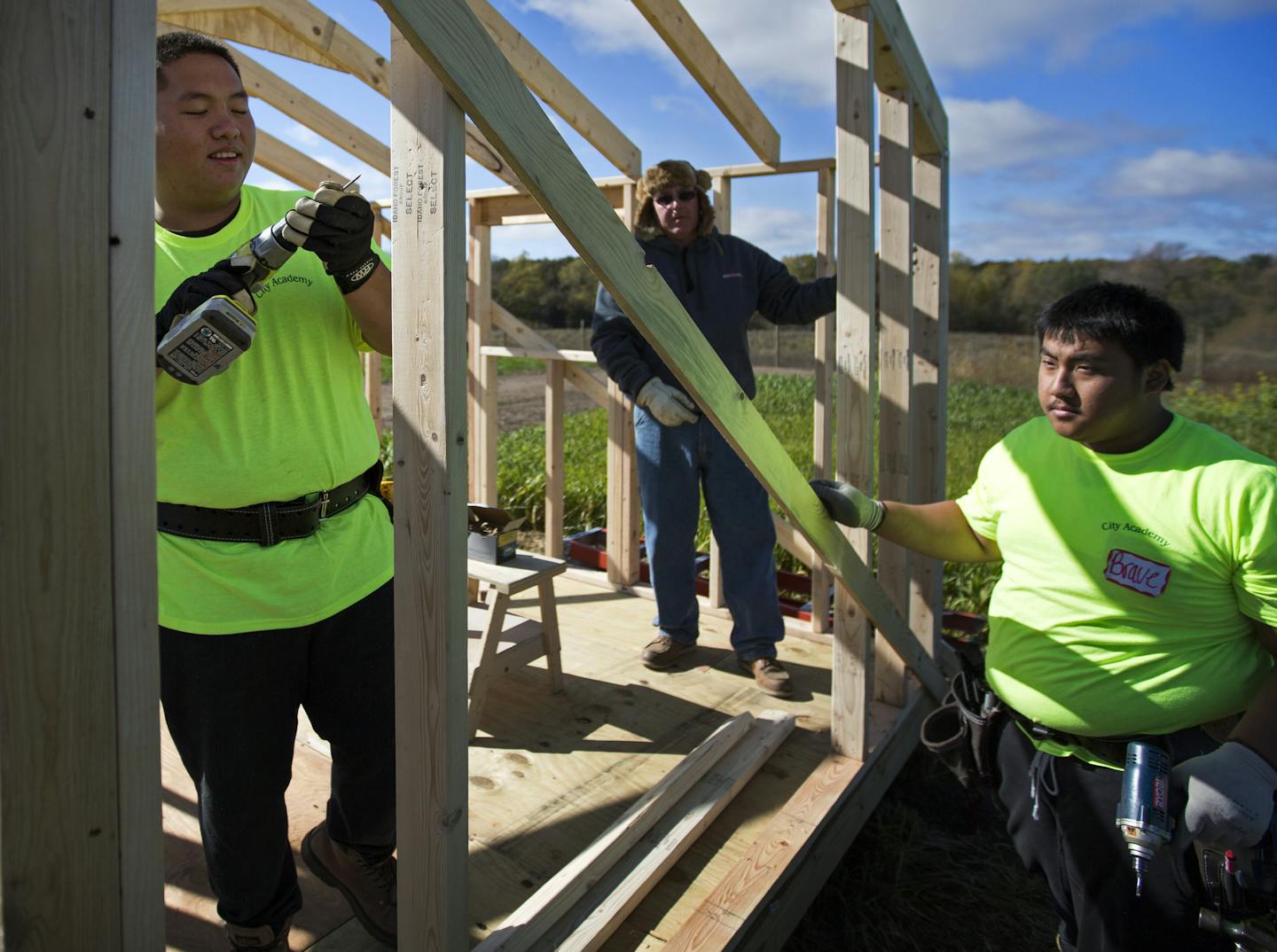 Leo Tomperi, an instructor for the carpenters union (center) helps Kong Thao, 18 (left) and Bravors Moua, 18 (right) build a storage shed on the MAFA property in Dakota County. ] High school students from across Minnesota are building storage sheds for the Hmong American Farmers Association at its research and incubator farm in Dakota County. Brian.Peterson@startribune.com Hastings, MN - 10/04/2015