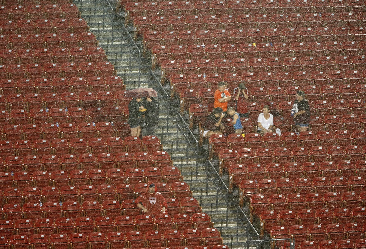 Fans attempt to wait out the rain as lightning rolls through the area, delaying the start of an MLS soccer match between Minnesota United and FC Dallas in Frisco, Texas, Saturday, Aug. 18, 2018. (Stewart F. House/The Dallas Morning News via AP)