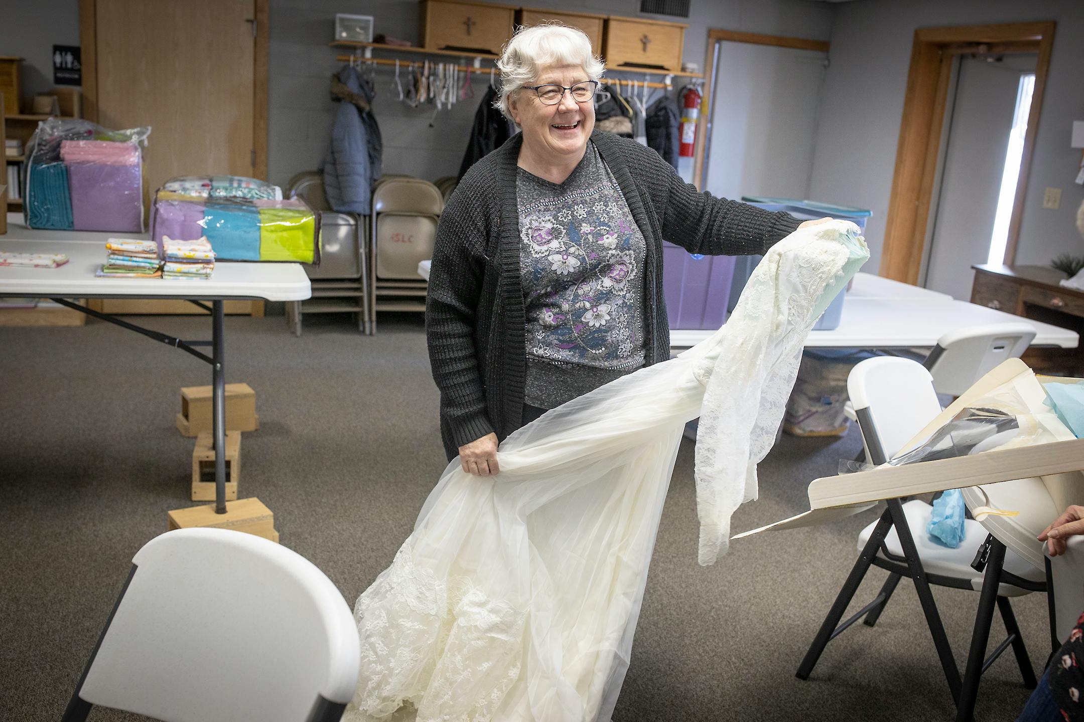 Patty Hauer, a retired coroner investigator takes out a used wedding dress that was donated to make "Angel Dresses" in the All Saints Lutheran Church basement in  Darwin, Minn.