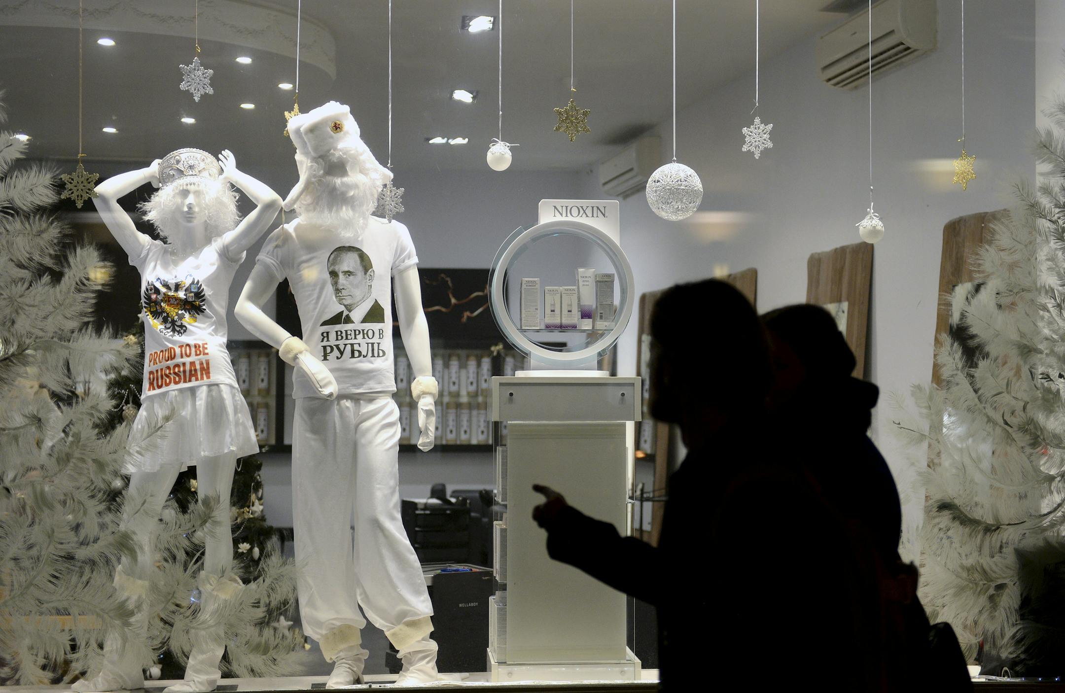 Pedestrians walk past a hairdresser‚Äôs salon in downtown Moscow, where the value of the ruble was in free fall the day after a dramatic middle-of-the-night interest rate hike, Dec. 16, 2014. The shirt with the face of President Vladimir Putin reads "I believe in the ruble." (James Hill/The New York Times) -- NO SALES