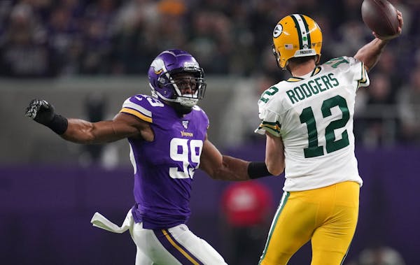 Green Bay Packers quarterback Aaron Rodgers (12) looked to throw under pressure from Minnesota Vikings defensive end Danielle Hunter (99) before being