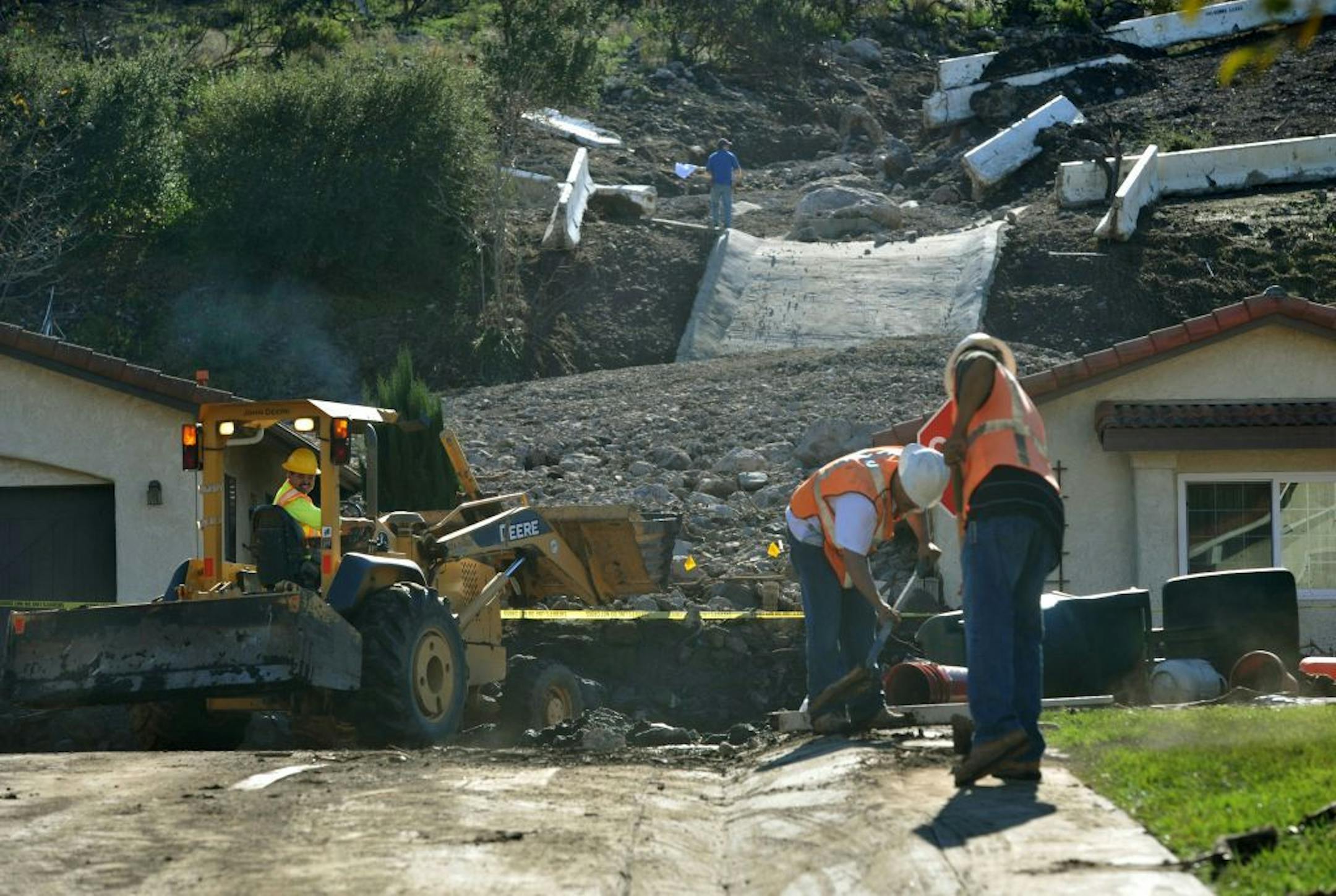 Work crews with Staben Bros. clean up debris after a rainstorm broke through k-rails and brought down mud and rocks into the homes of Camarillo Springs residents in Camarillo, Calif, Saturday, Dec. 13, 2014. Over a dozen homes in the area were damaged and ten were left unsafe to live in or even enter after the storm. (AP Photo/Ventura County Star, Joseph A. Garcia) LOS ANGELES DAILY NEWS OUT