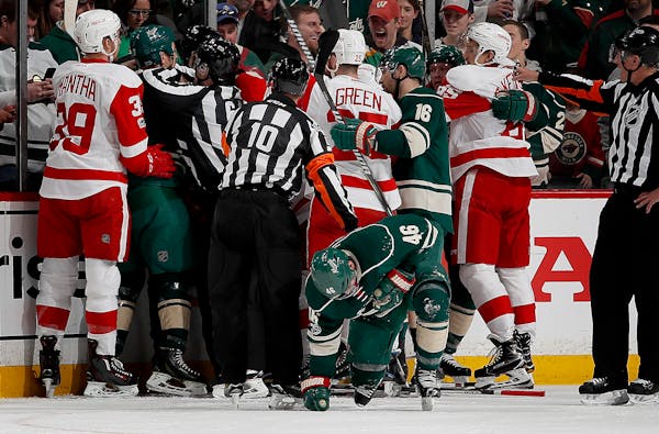 The Wild and Red Wings converge as Jared Spurgeon (46) tried to get up off the ice after taking a stick to the face in the first period