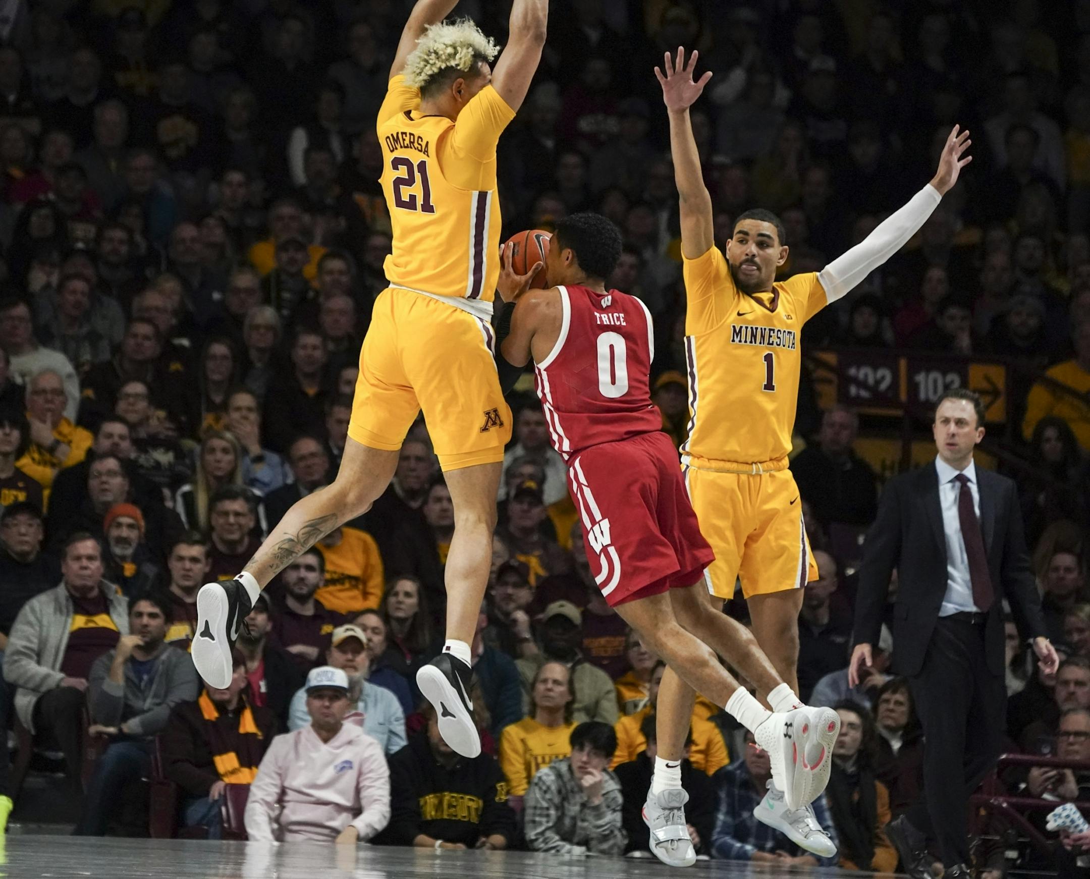Wisconsin Badgers guard D'Mitrik Trice (0) was stopped by Minnesota Gophers forward Jarvis Omersa (21) as he jumped for a shot in the first half.