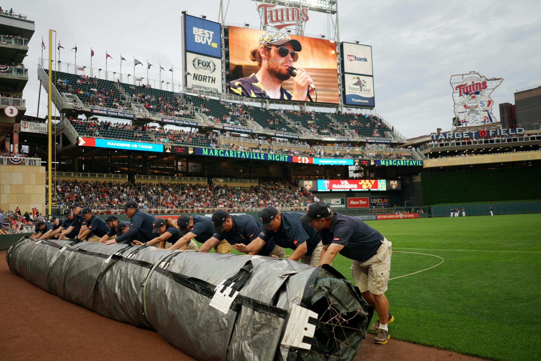 Members of the grounds crew removed the tarp from the infield following rain delay Friday at Target Field.