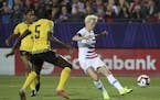 United States forward Megan Rapinoe scores a goal while being defended by Jamaica defender Konya Plummer during the first half of a CONCACAF women's W