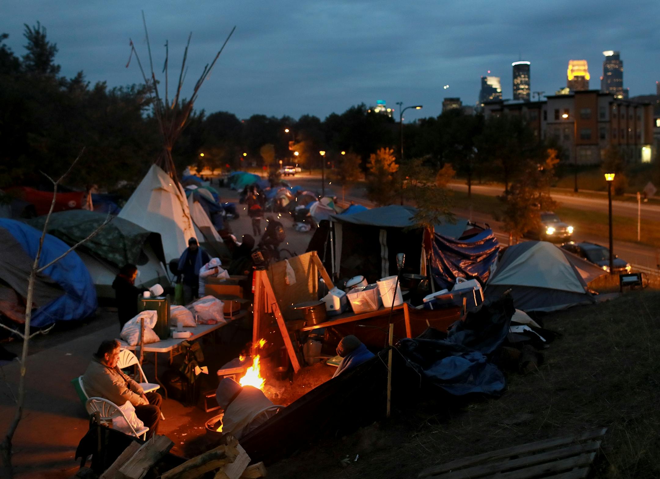 Homeless residents of a large homeless encampment stay warm by a fire Thursday, Oct. 4, 2018, in Minneapolis, MN.