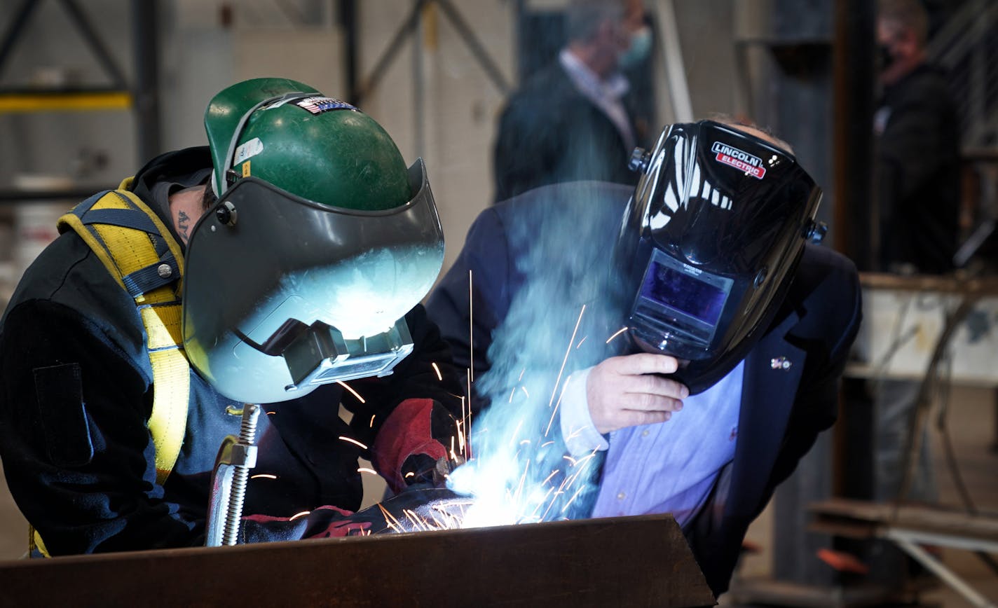 Governor Tim Walz, right, watched as Travis Sturges put the finishing touches on a steel thank you beam for him after he signed the $1.9 billion bonding bill. Earlier Josh Kalina carved the actual words Thank You. ] GLEN STUBBE • glen.stubbe@startribune.com Wednesday, October 21, 2020 Governor Tim Walz was joined by union leaders at the Ironworkers Local 512 Training Center in St. Paul as he signed the $1.9 billion bonding bill.