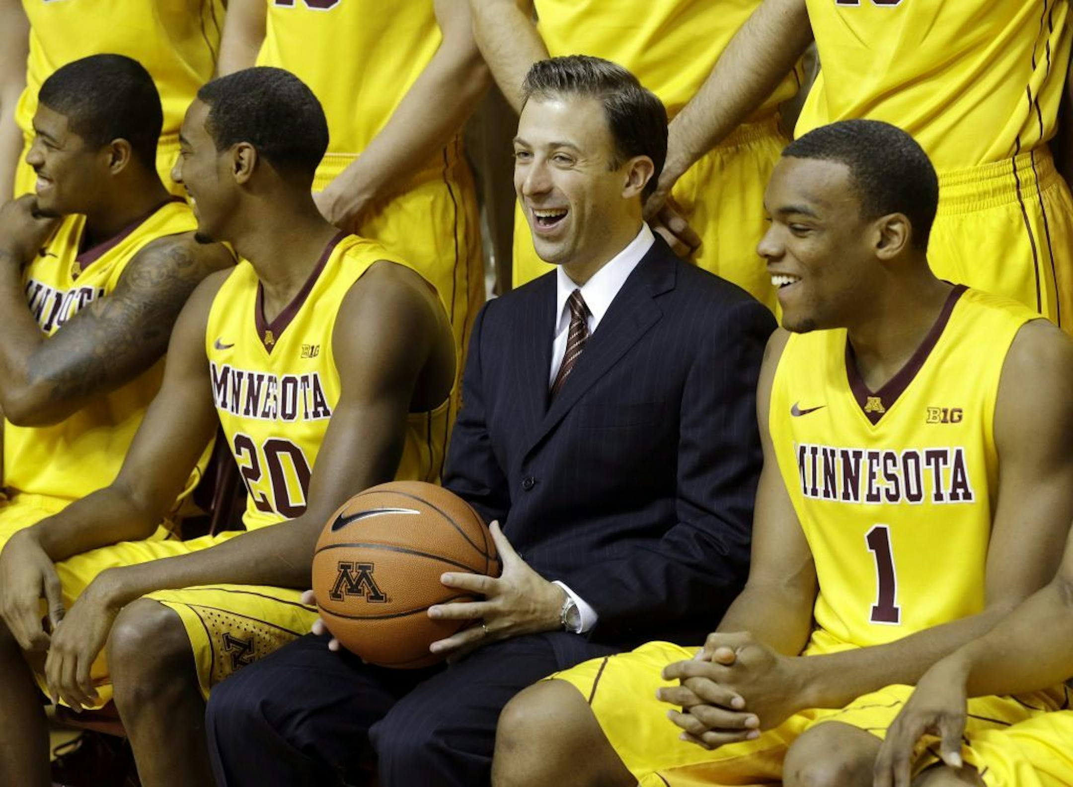 New Minnesota head basketball coach Richard Pitino, center, enjoys a laugh along with, from left, Maverick Ahanmisi, Austin Hollins and right, Andre Hollins (no relation) during set up for the formal team portrait during media day, Monday, Oct. 28, 2013, in Minneapolis.