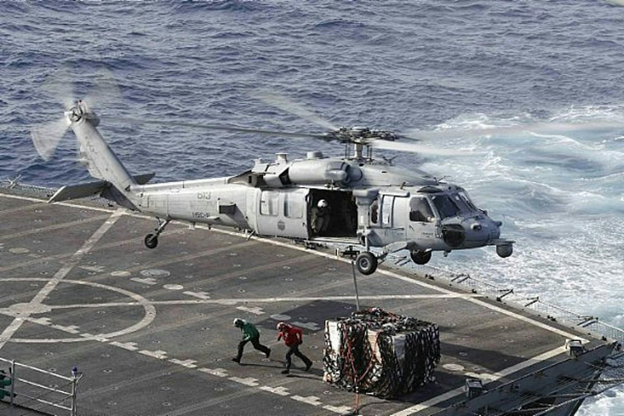 In this Sunday, May 19, 2019 photo, an MH-60S Sea Hawk helicopter transports cargo from the fast combat support ship USNS Arctic to the Nimitz-class aircraft carrier USS Abraham Lincoln during a replenishment-at-sea operation in the Arabian Sea, as Mideast tensions remain high between Tehran and the United States.