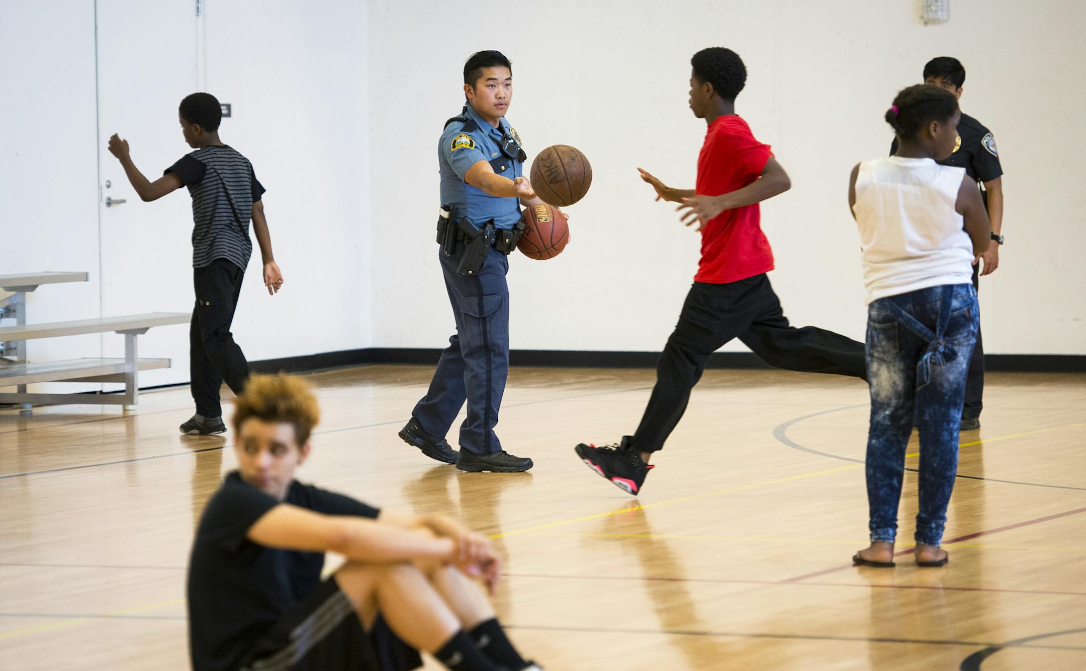 Officer Pheng Xiong handed a basketball to Ronnie Kemp, 15, at the Arlington Hills Community Center. Xiong takes his role as a mentor seriously.