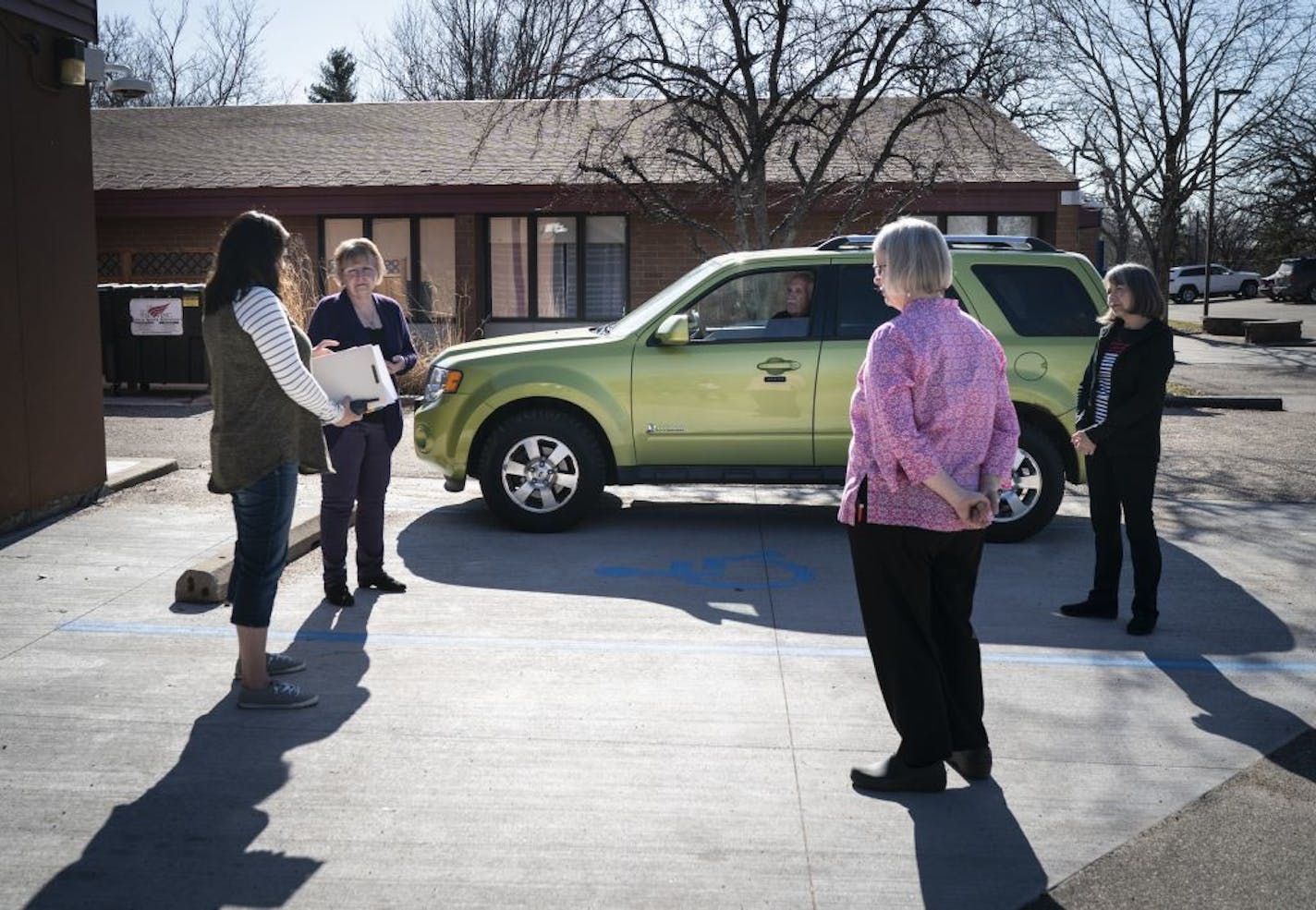 Dr. John Goeppinger, 71, sat in his car in the C.A.R.E. Clinic parking lot while (from the left) executive director and RN Julie Malyon, retired RN Cindy Larson, student Nurse practitioner Holly Girdeen and RN Verna Fricke met with him to have a meeting in Red Wing, Minn., on Tuesday, March 31, 2020. Goeppinger is a retired family medicine doctor who is volunteering for the clinic but keeping his distance by staying in his car and consulting with nurses due to the Covid-19 epidemic.