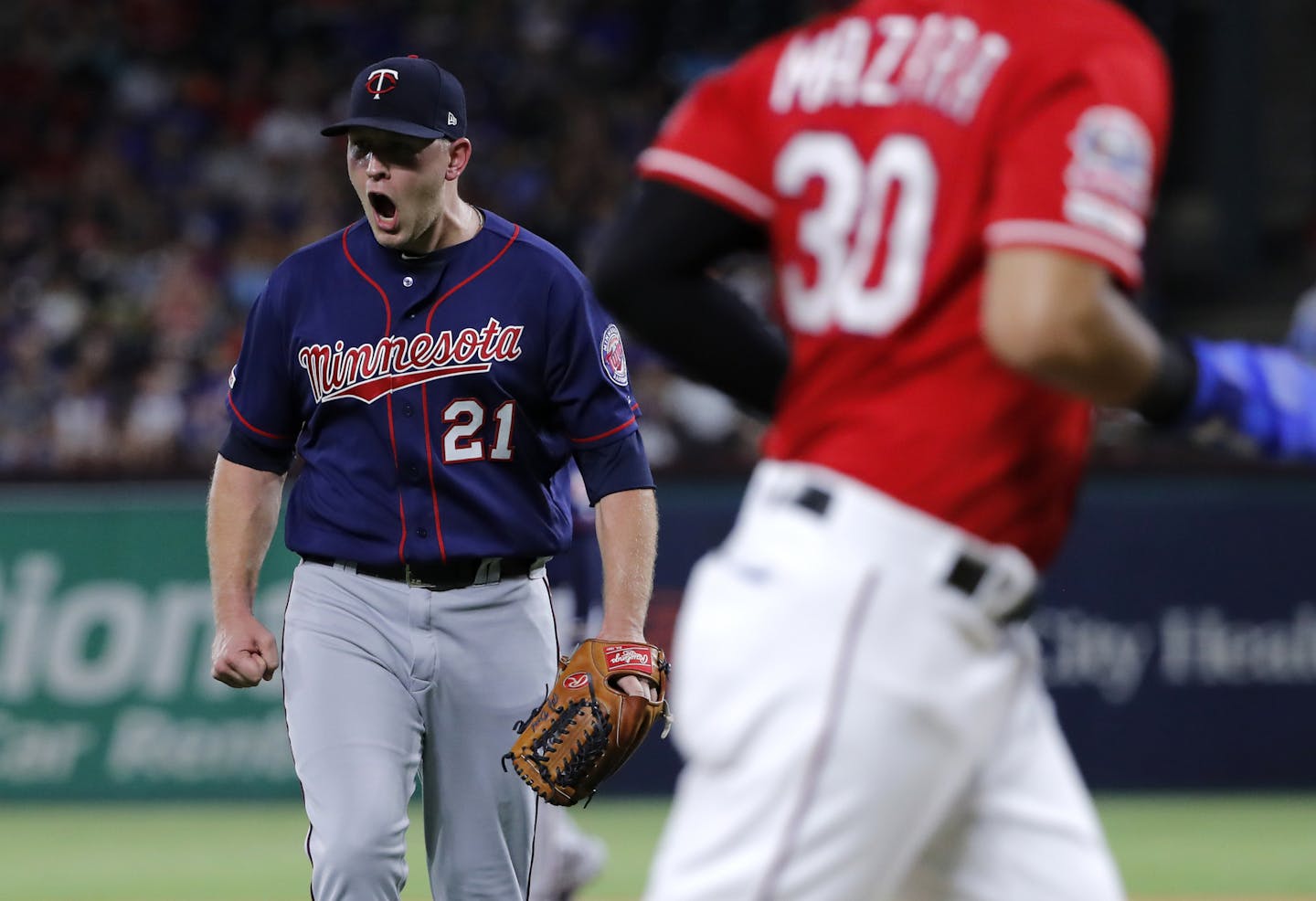 Texas Rangers' Nomar Mazara jogs to the dugout as Minnesota Twins relief pitcher Tyler Duffey (21) celebrates getting Isiah Kiner-Falefa to fly out with the bases loaded, ending the fifth inning of a baseball game in Arlington, Texas, Saturday, Aug. 17, 2019. (AP Photo/Tony Gutierrez)