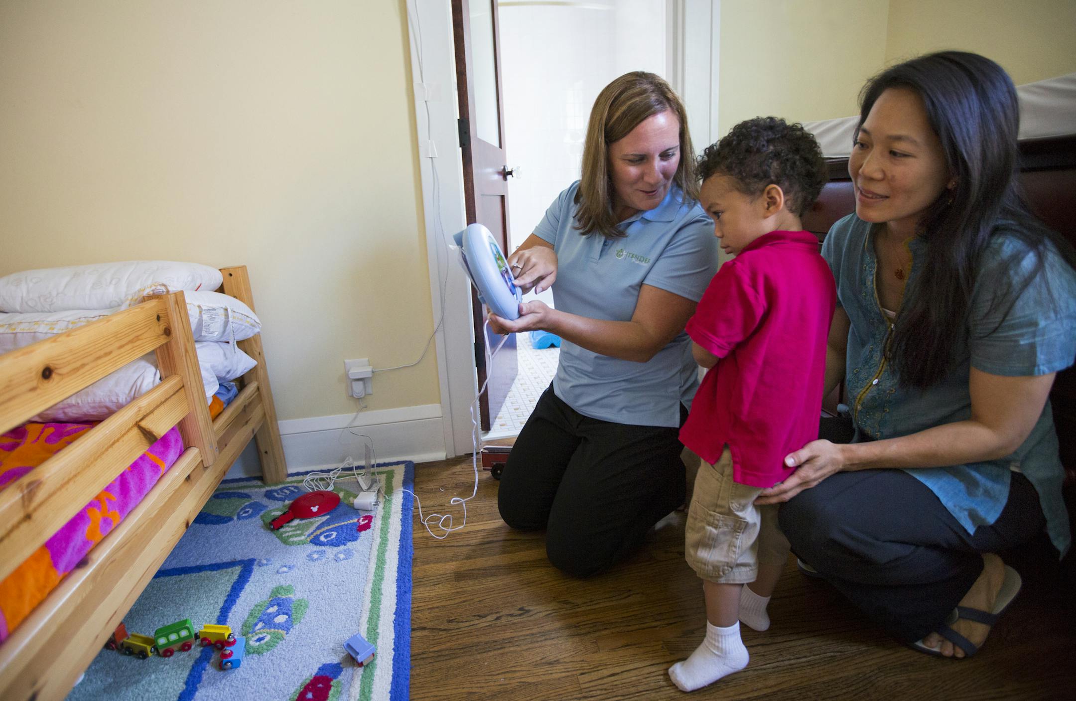 Sleep consultant Leann Latus (left) shows mother Marie Shau and her 2-year-old son Milo a sleep clock that could help him better understand his sleep routine. ] Brian.Peterson@startribune.com Minneapolis, MN - 7/13/2015