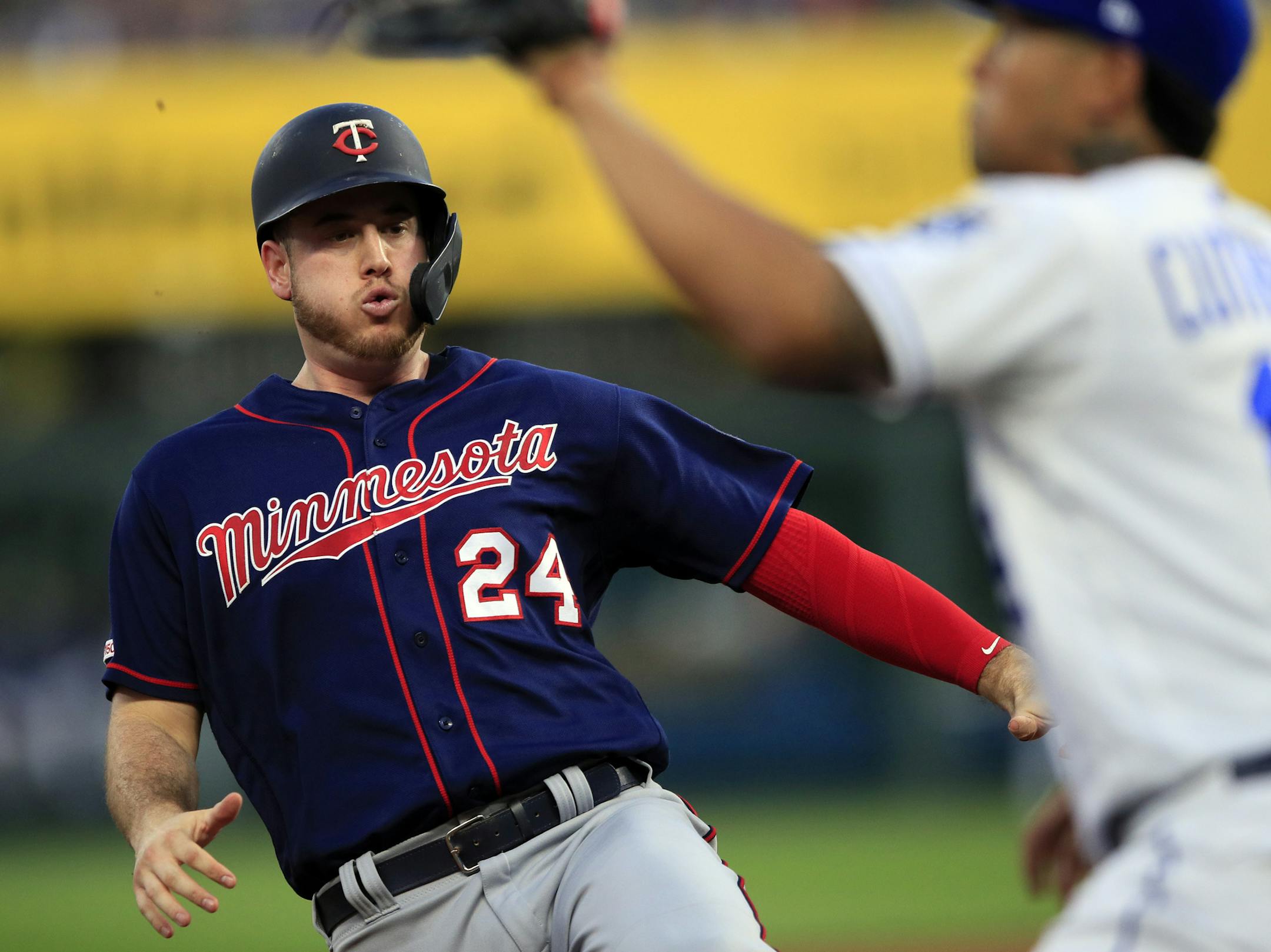 Minnesota Twins' C.J. Cron (24) slides into third base and beats the tag by Kansas City Royals third baseman Cheslor Cuthbert, right, while advancing from first on a single by Luis Arraez during the fourth inning of a baseball game at Kauffman Stadium in Kansas City, Mo., Thursday, June 20, 2019. (AP Photo/Orlin Wagner)