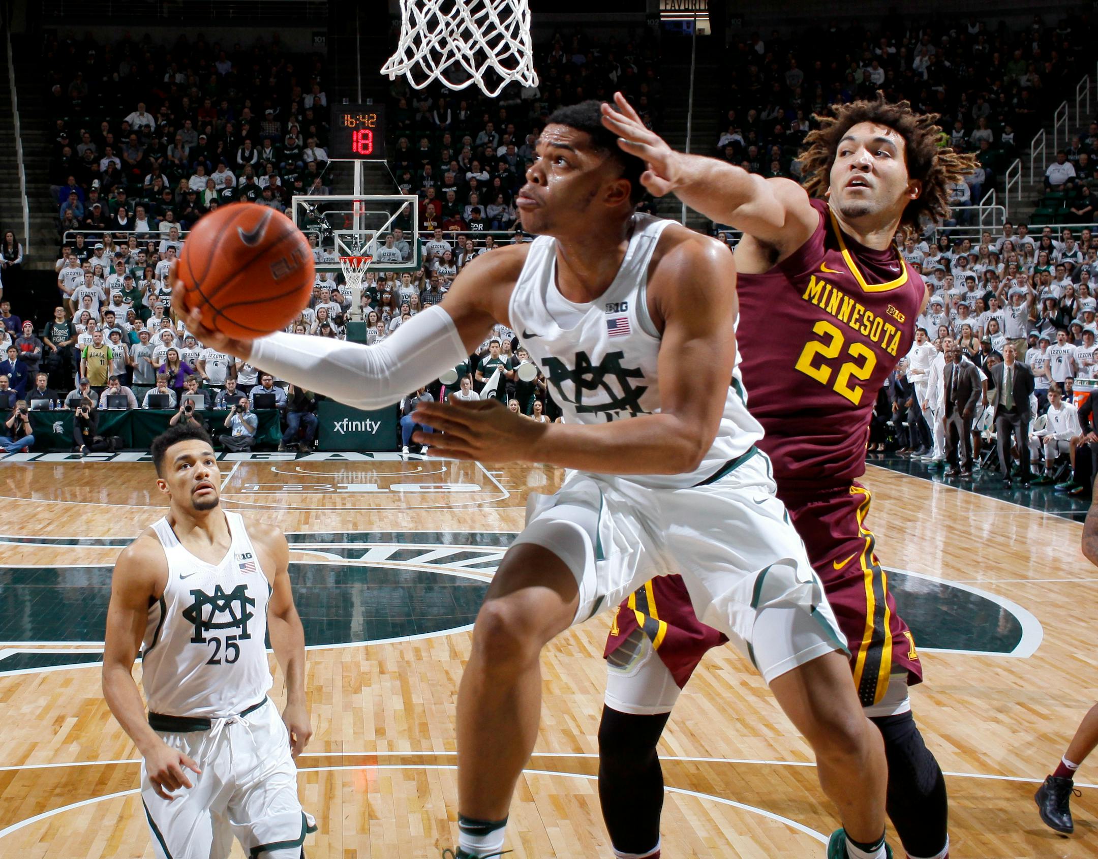 Michigan State's Miles Bridges, center, puts up a reverse layup against Minnesota's Reggie Lynch (22) as Michigan State's Kenny Goins, left, watches during the first half of an NCAA college basketball game on Wednesday in East Lansing, Mich.
