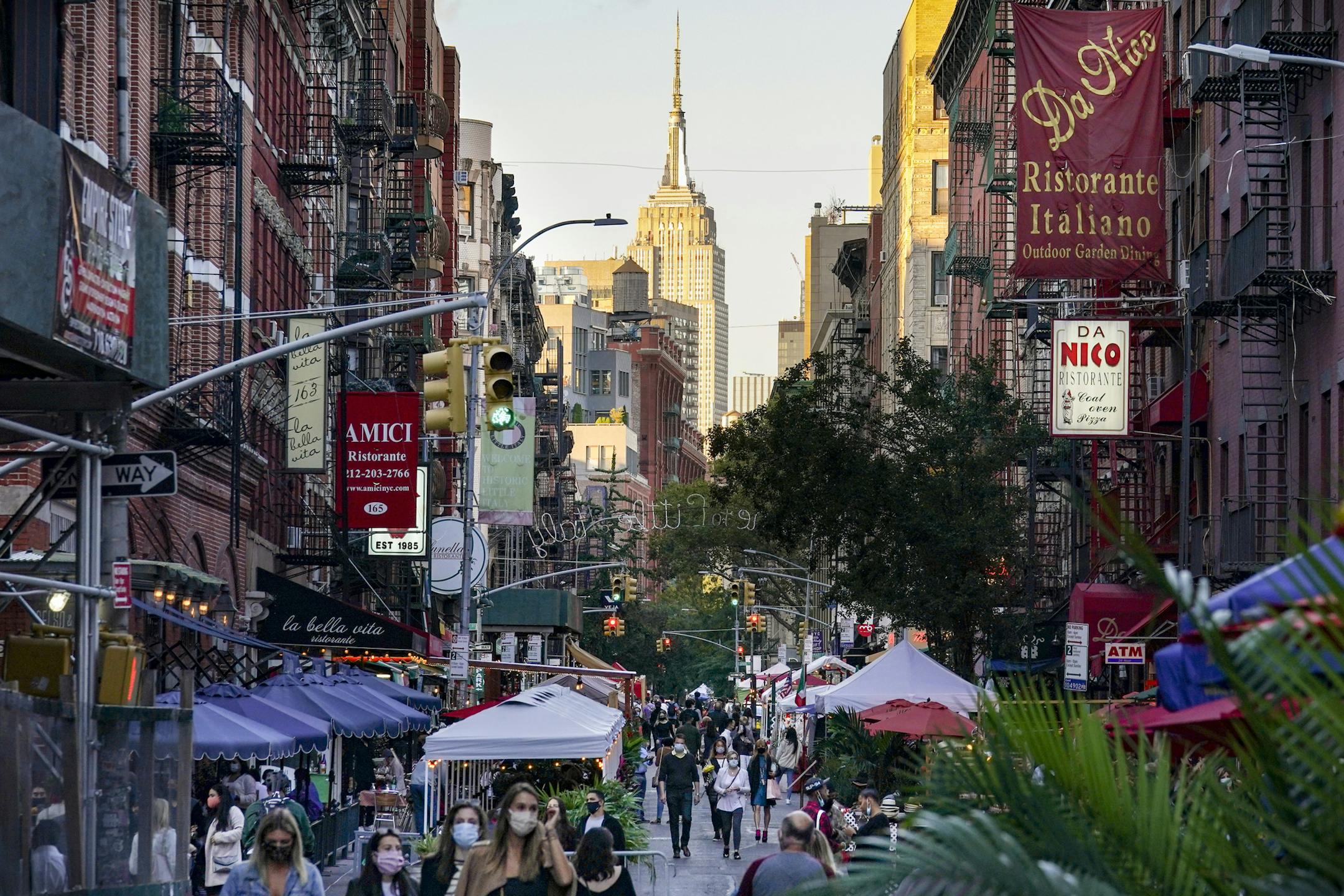 People walk through an area where restaurants operate outdoor spaces for dining that spread onto sidewalks and streets as part of continued COVID-19 economic impact mitigation efforts, Saturday, Oct. 3, 2020, in New York. (AP Photo/John Minchillo)