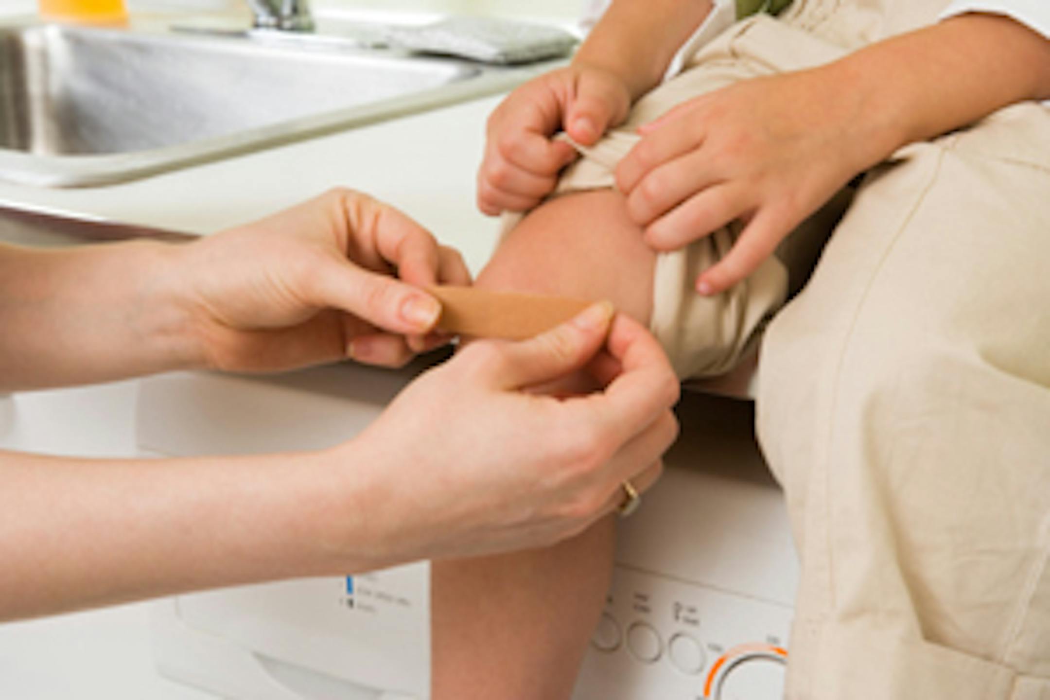 Mother putting bandage on daughter