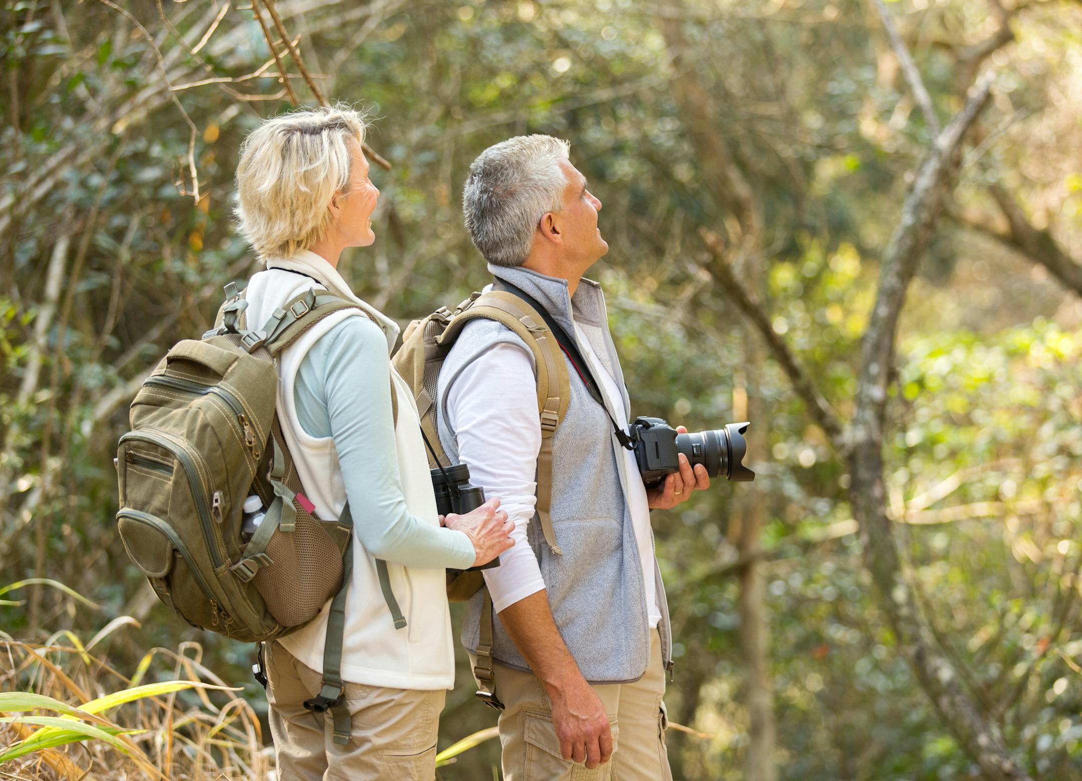 cheerful middle aged couple bird watching in forest. istock