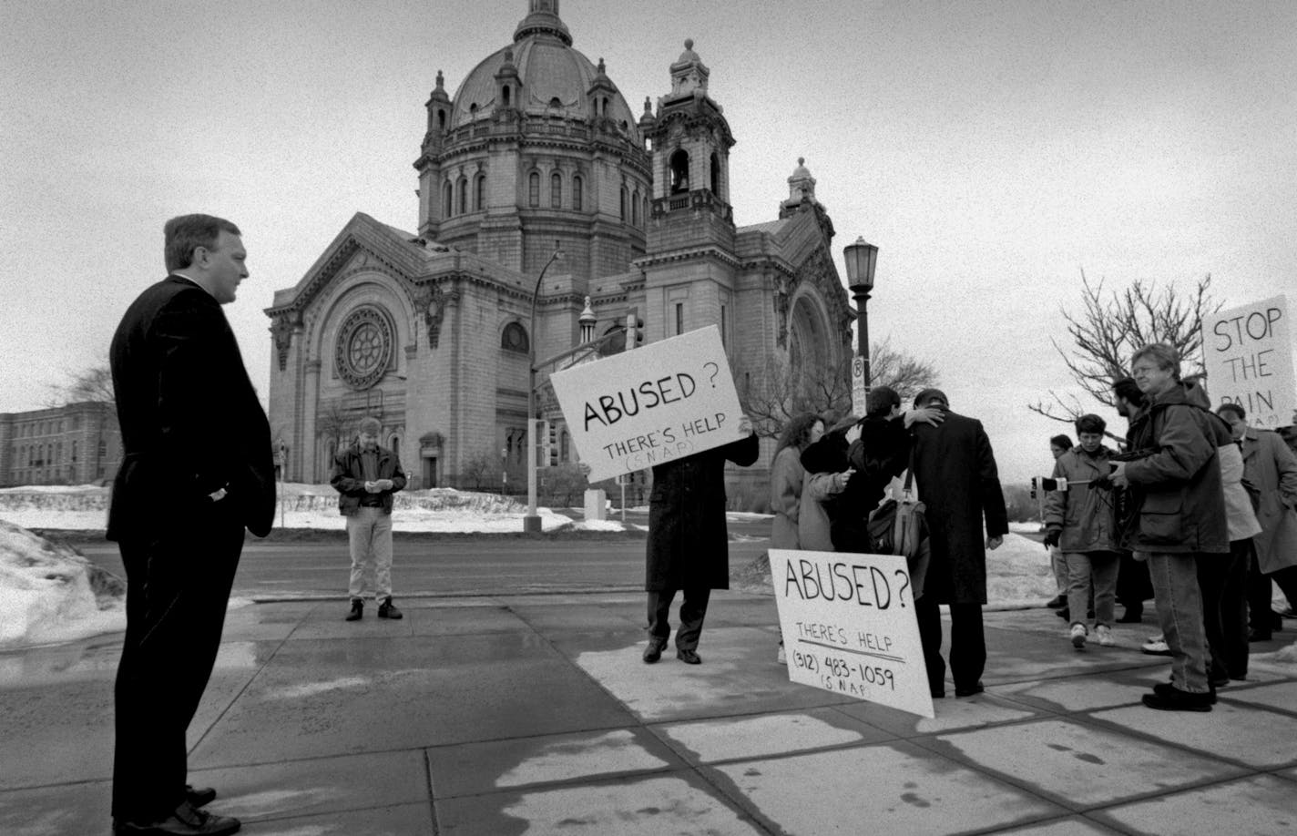 Kevin McDonough (left), vicar general of the Archdiocese of St. Paul and Minneapolis, watches a rally by adults claiming to be victims of sexual abuse as children by Catholic clergy. (Also at the rally were family members and supporters. The rally and press conference was held in front of the Chancery Office of the Archdiocese, across the street from the Cathedral. After the rally, McDonough responded to media questions. ORG XMIT: MIN2013102616084727