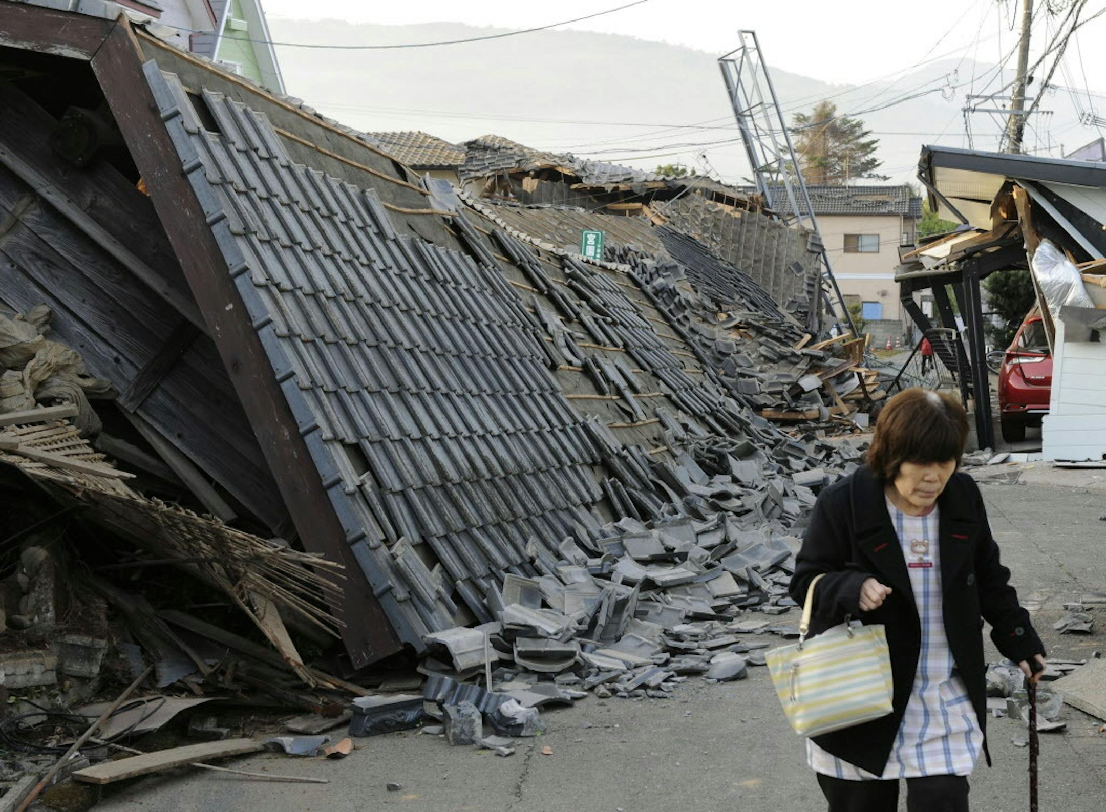 A resident walks past collapsed houses in Mashiki, Kumamoto prefecture, southern Japan, Friday, April 15, 2016, after a magnitude-6.5 earthquake.